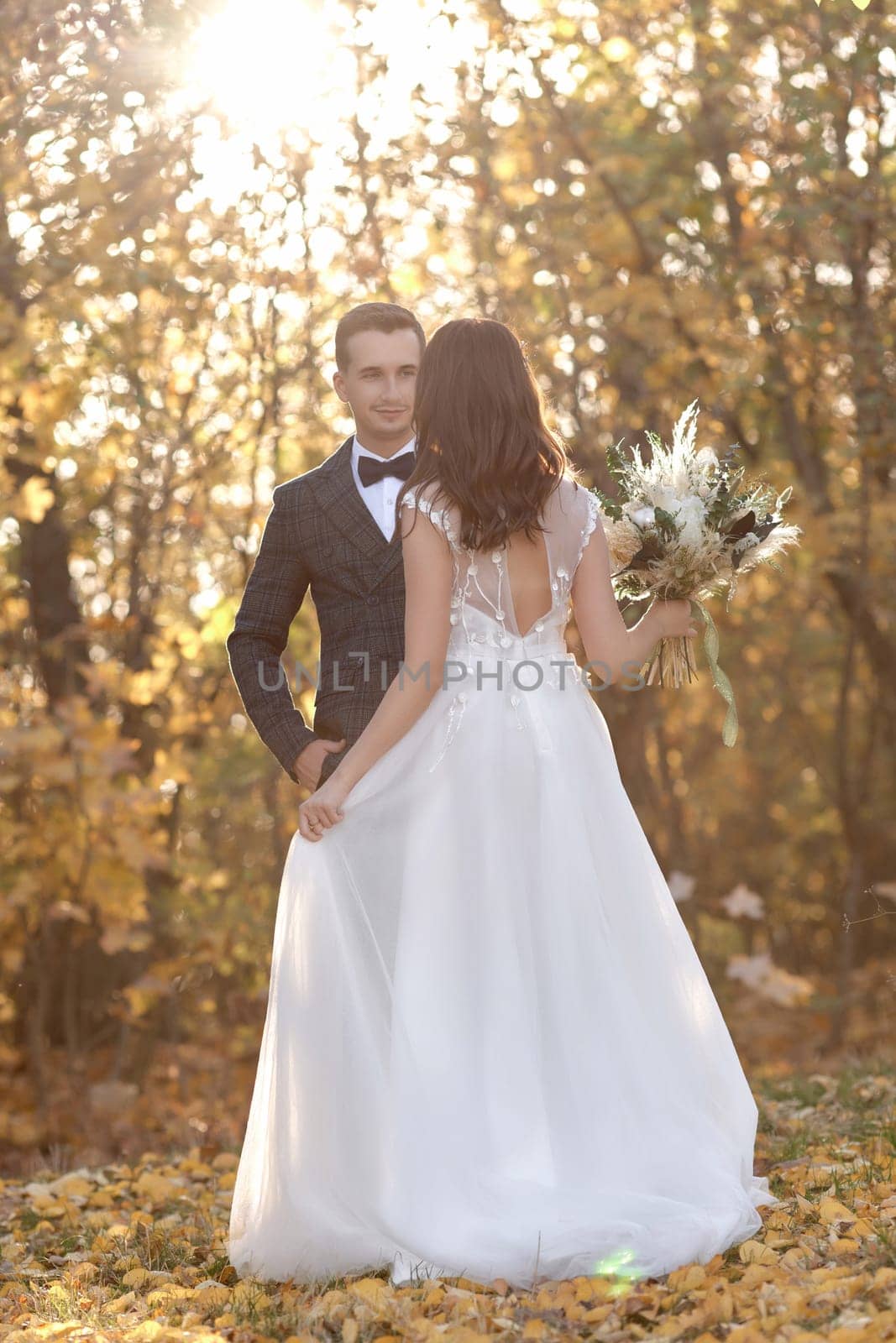 beautiful bride in white wedding dress and groom standing outdoor on natural background in sunny day