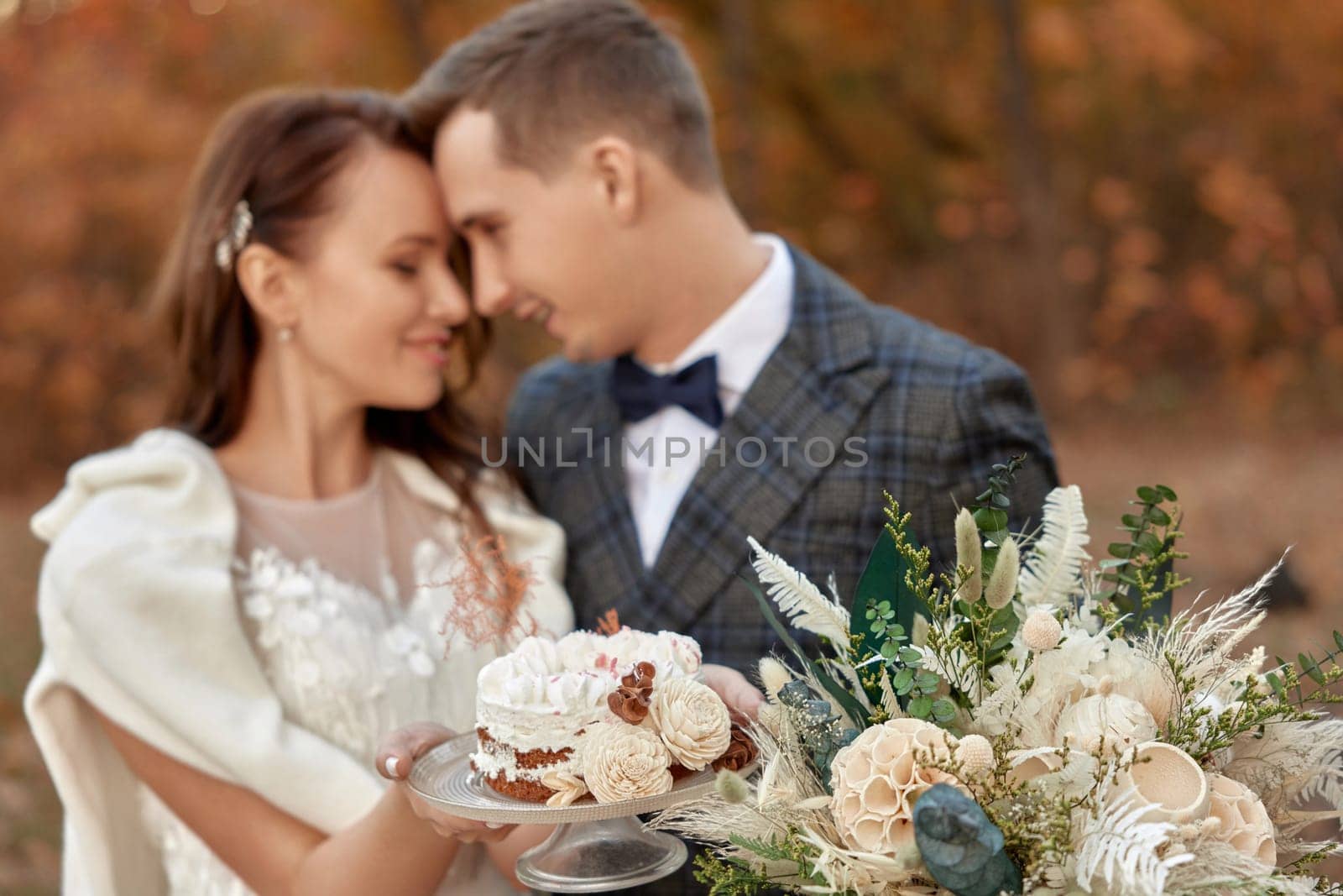 bride and groom on the nature in autumn . wedding couple with cake outdoor