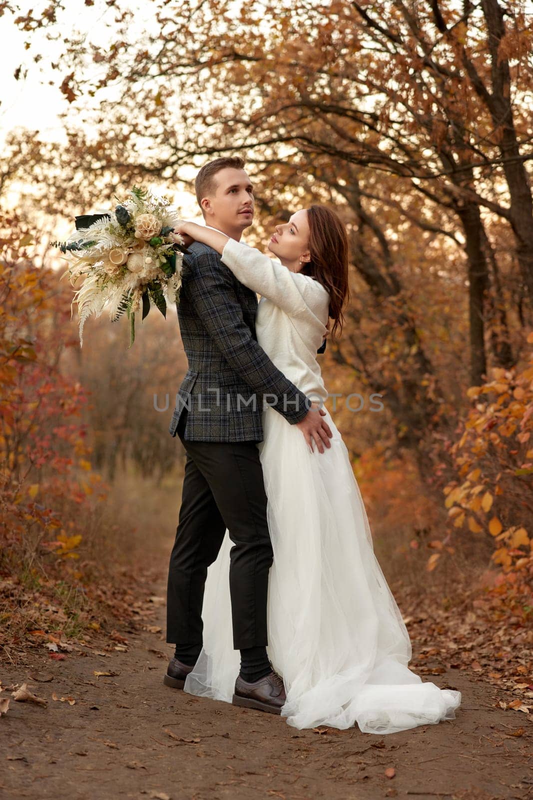 beautiful sensual bride in white wedding dress and groom standing outdoor on natural background