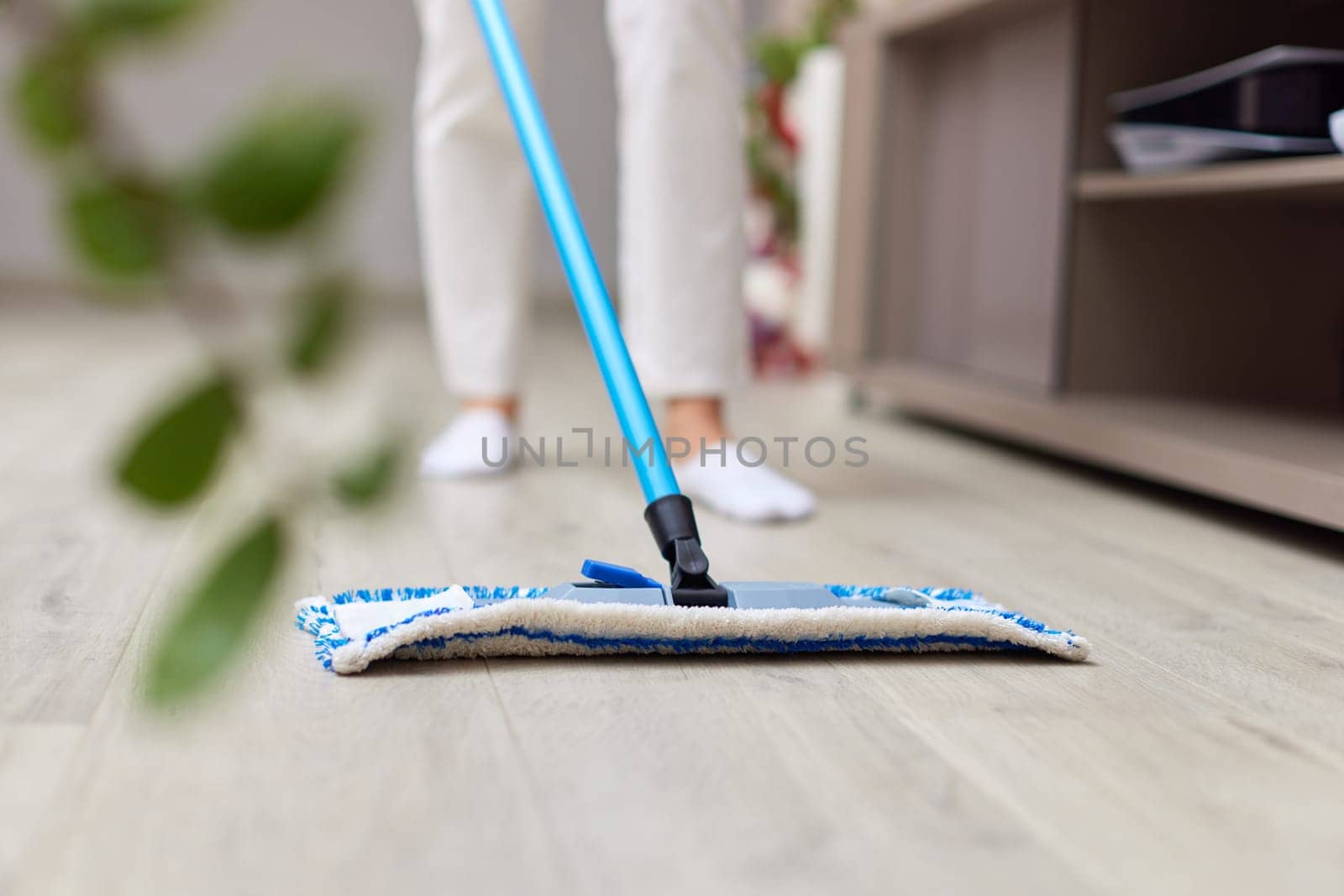 young woman cleaning and mopping floor at living room, daily housekeeping , close-up