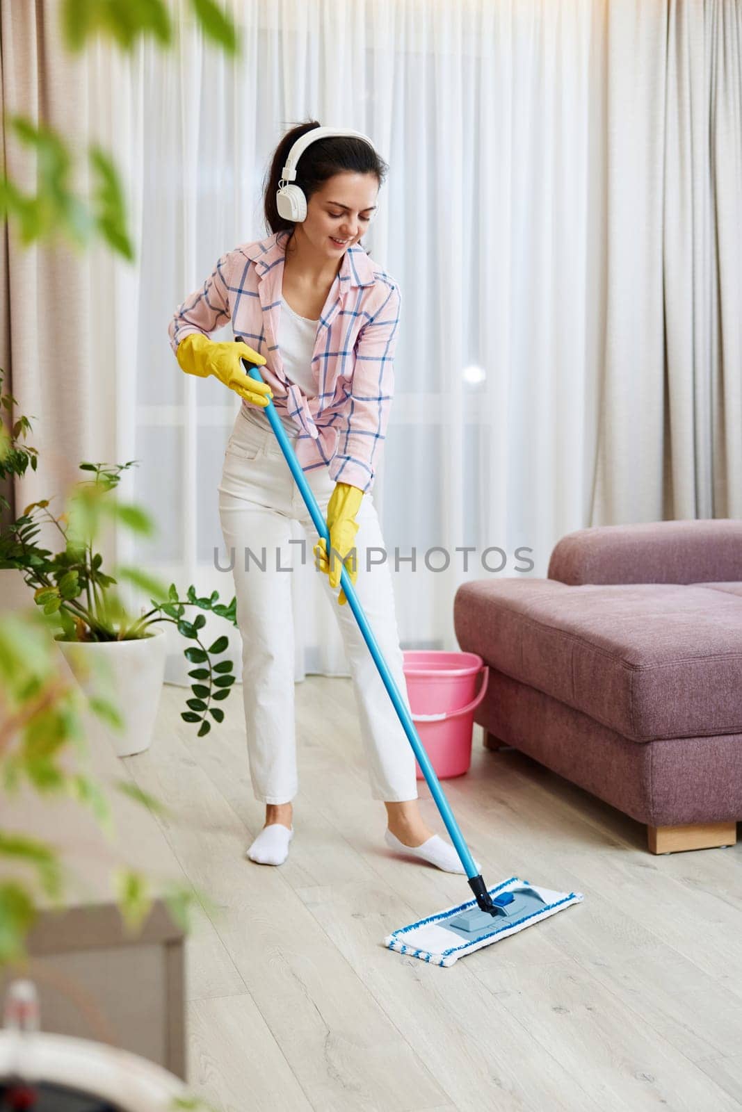 Happy woman singing and washing floor at living room, house chores.