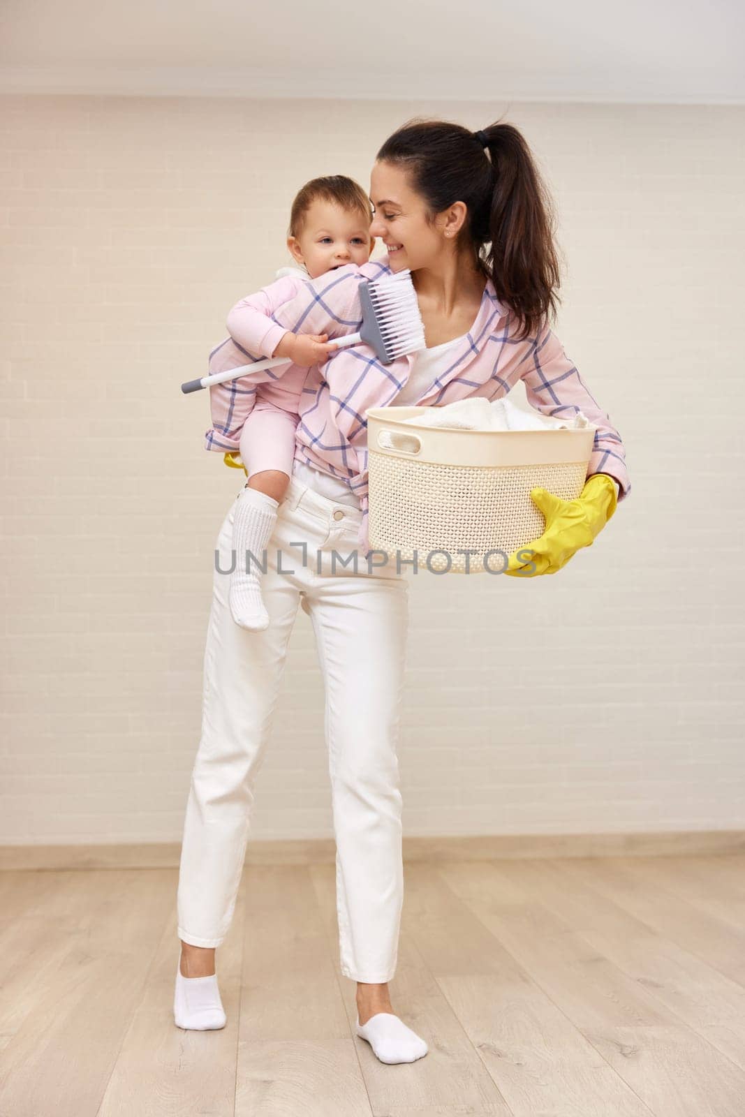 happy mother housewife is holding cute baby girl and basket with laundry , Happy family