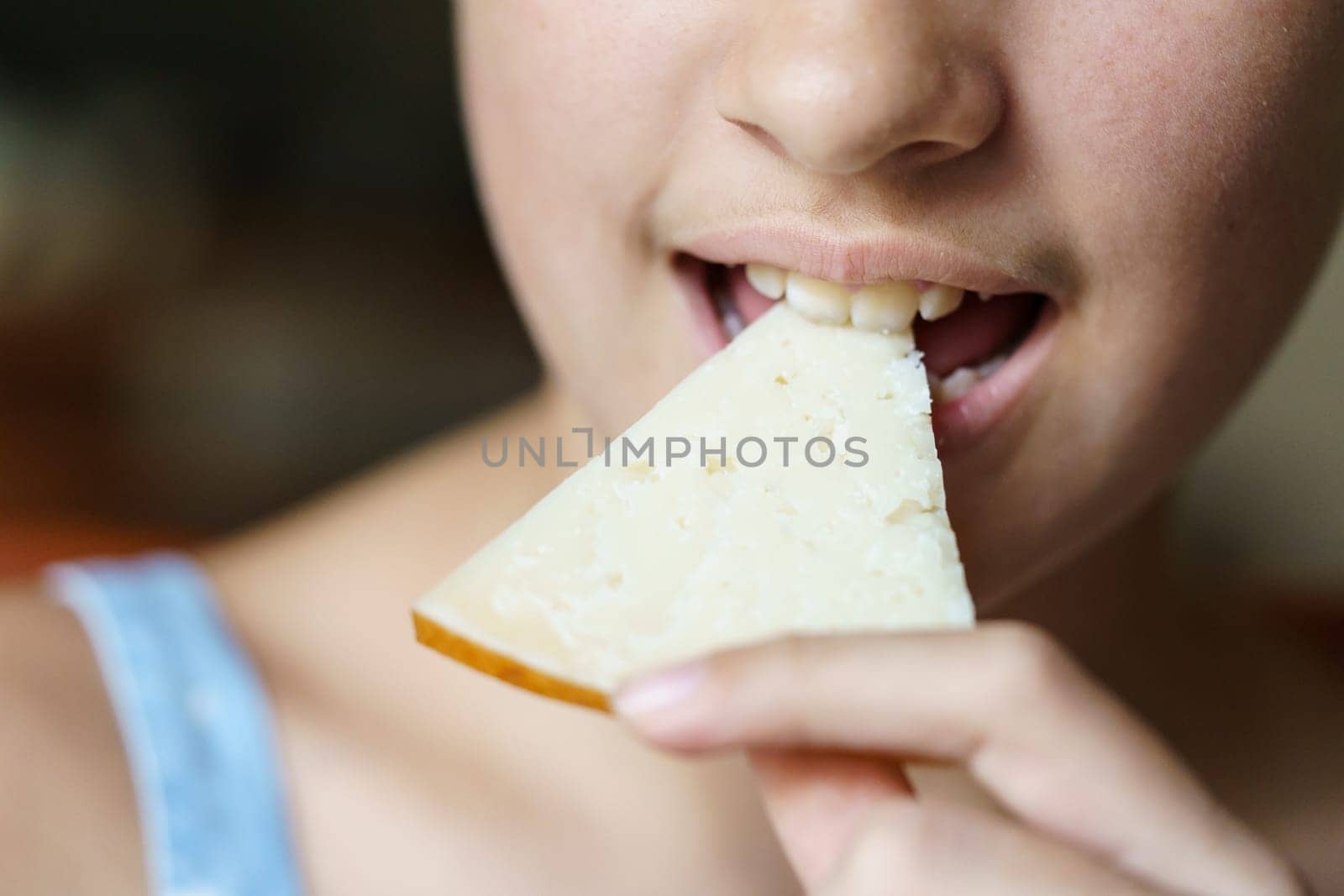 Closeup of unrecognizable teenage girl eating delicious cheese slice at home
