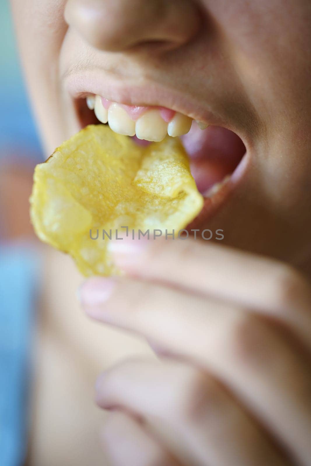 Unrecognizable teenage girl eating crunchy potato chip by javiindy