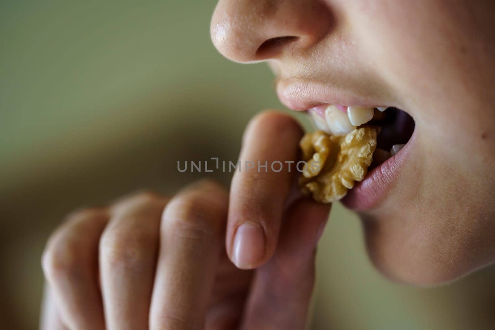 Side view of crop anonymous young girl eating fresh healthy walnut at home