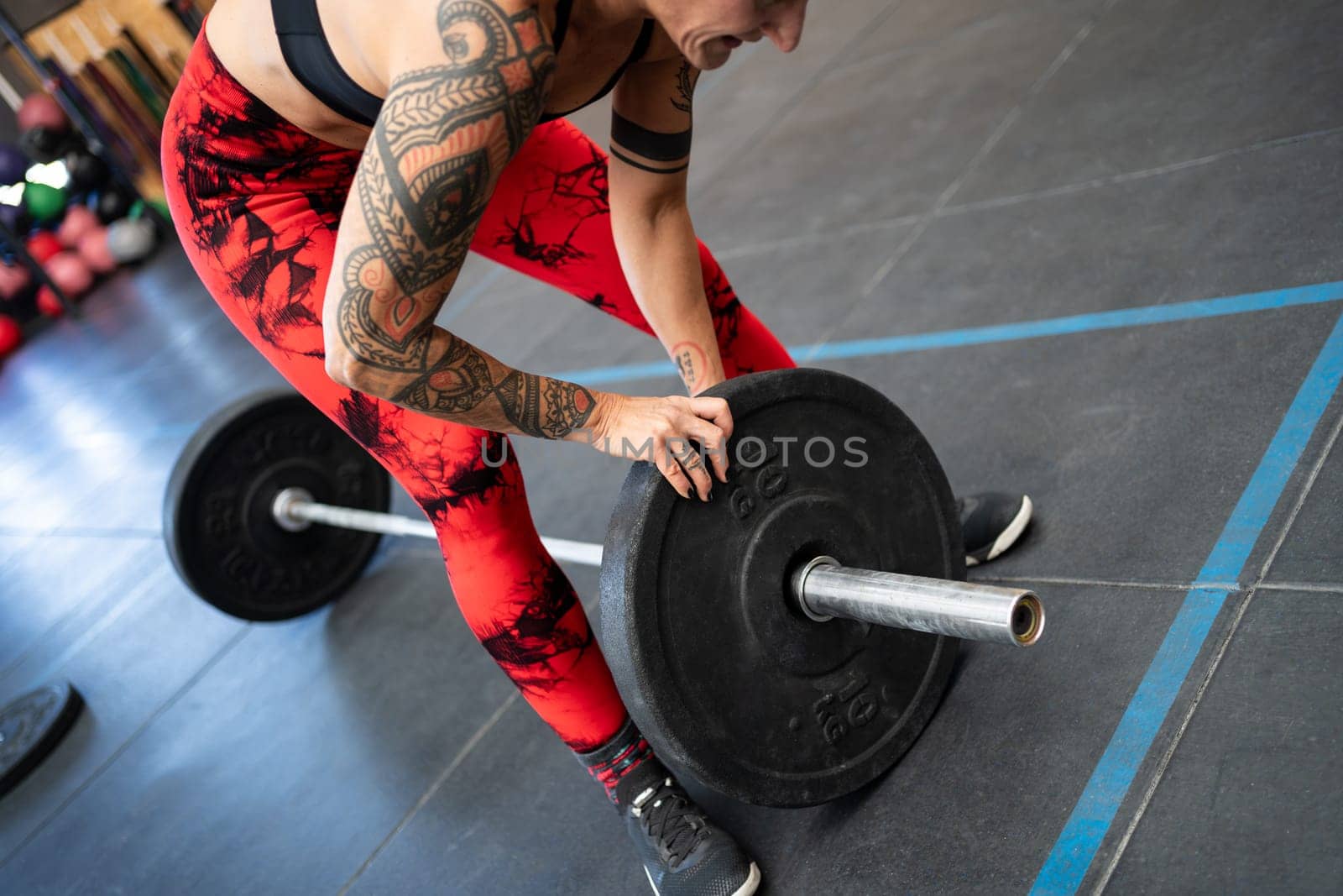 Close-up of an unrecognizable fit woman adding weight plates to a bar for weightlifting