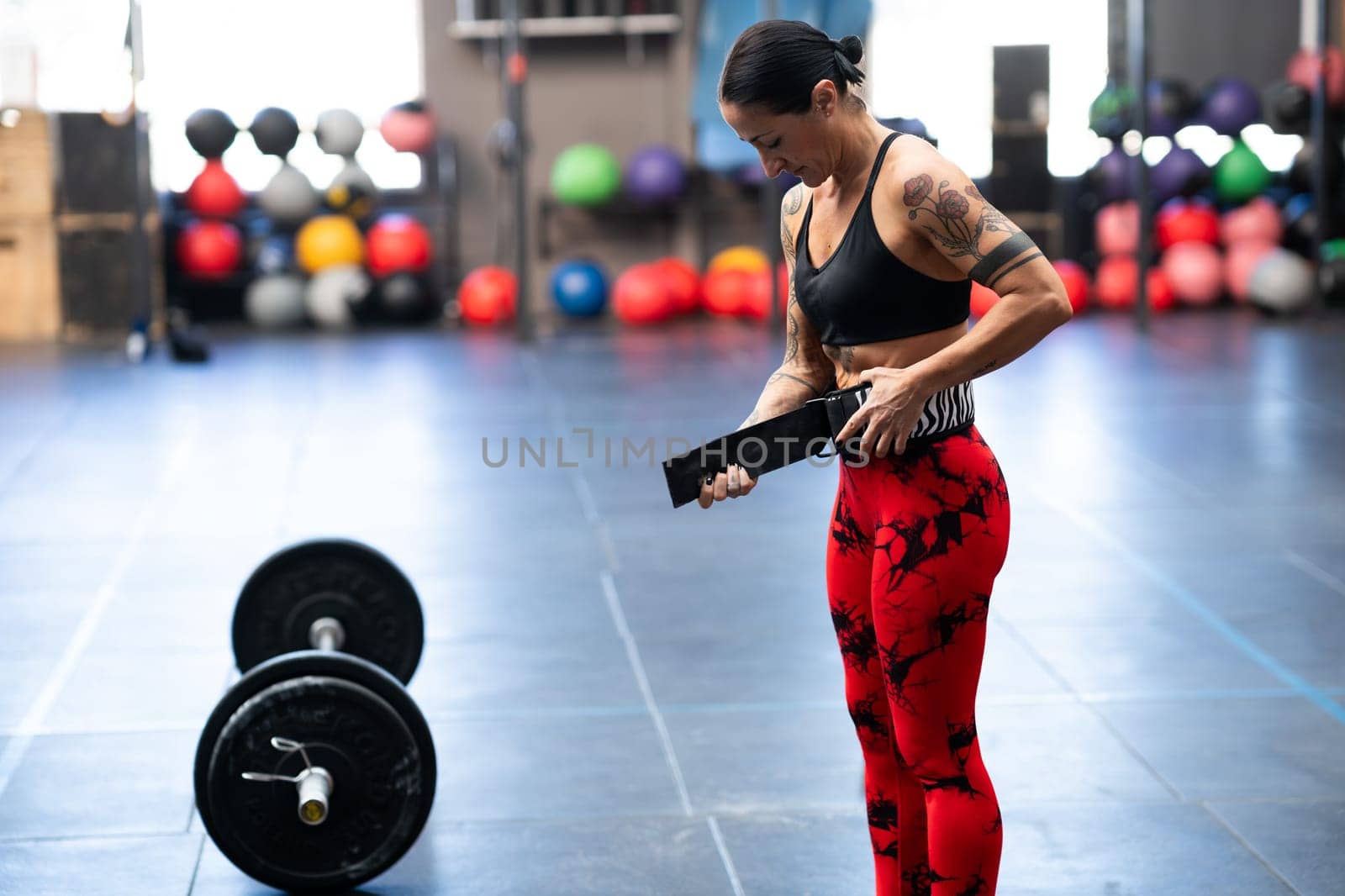 Strong woman preparing to weightlifting using safety belt in a cross training gym