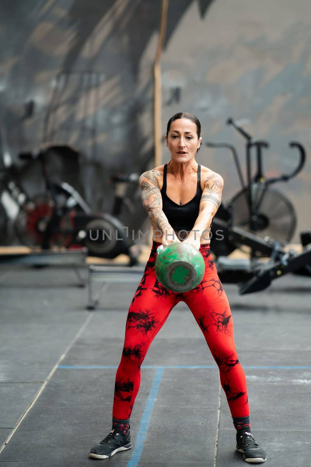 Woman performing kettlebell swing exercise in a gym by javiindy