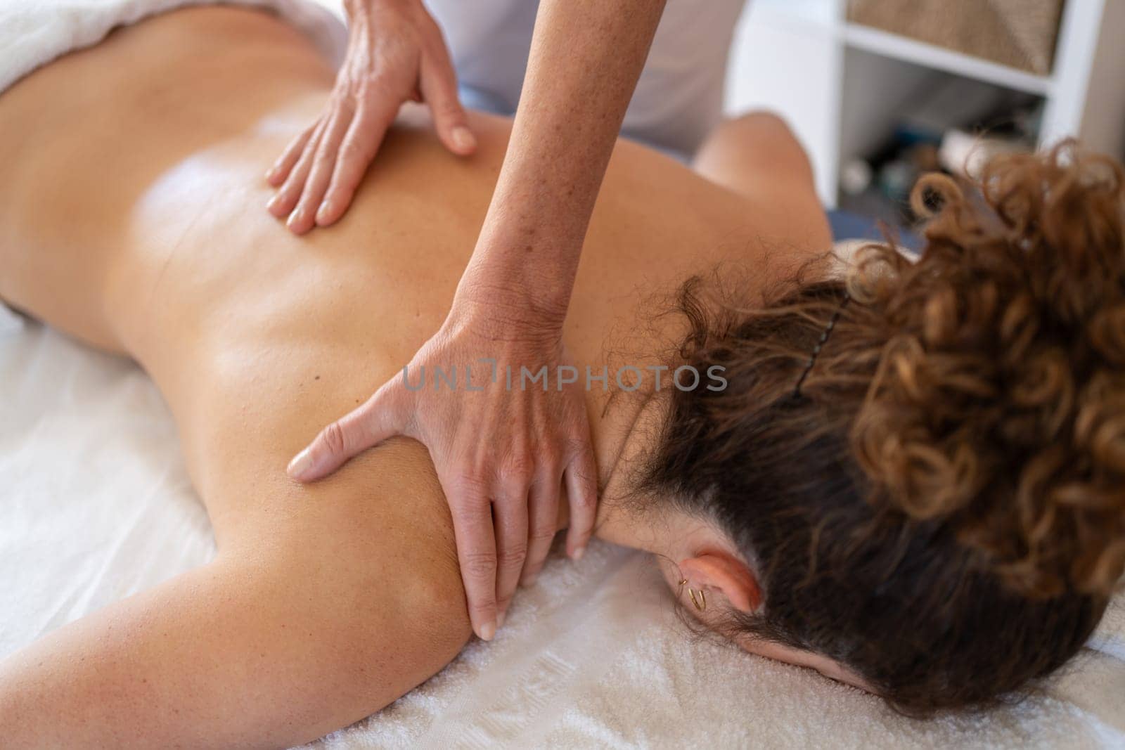 Crop masseuse kneading back of client in hospital room by javiindy