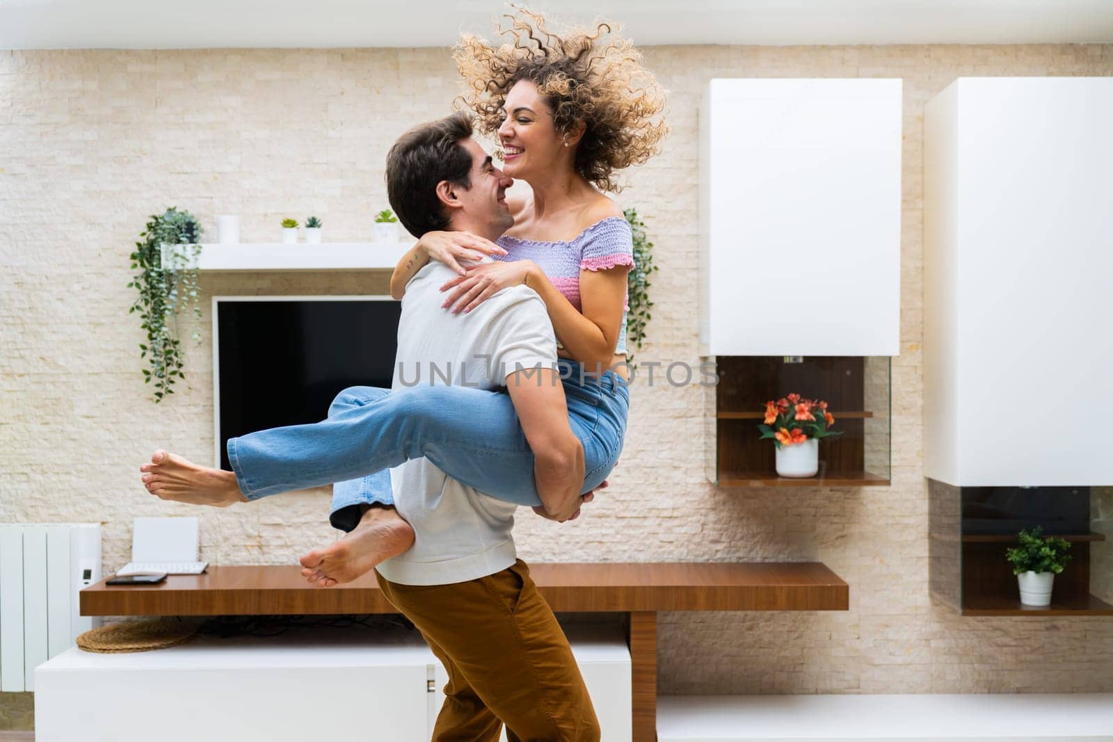 Happy young couple embracing while having fun at home by javiindy