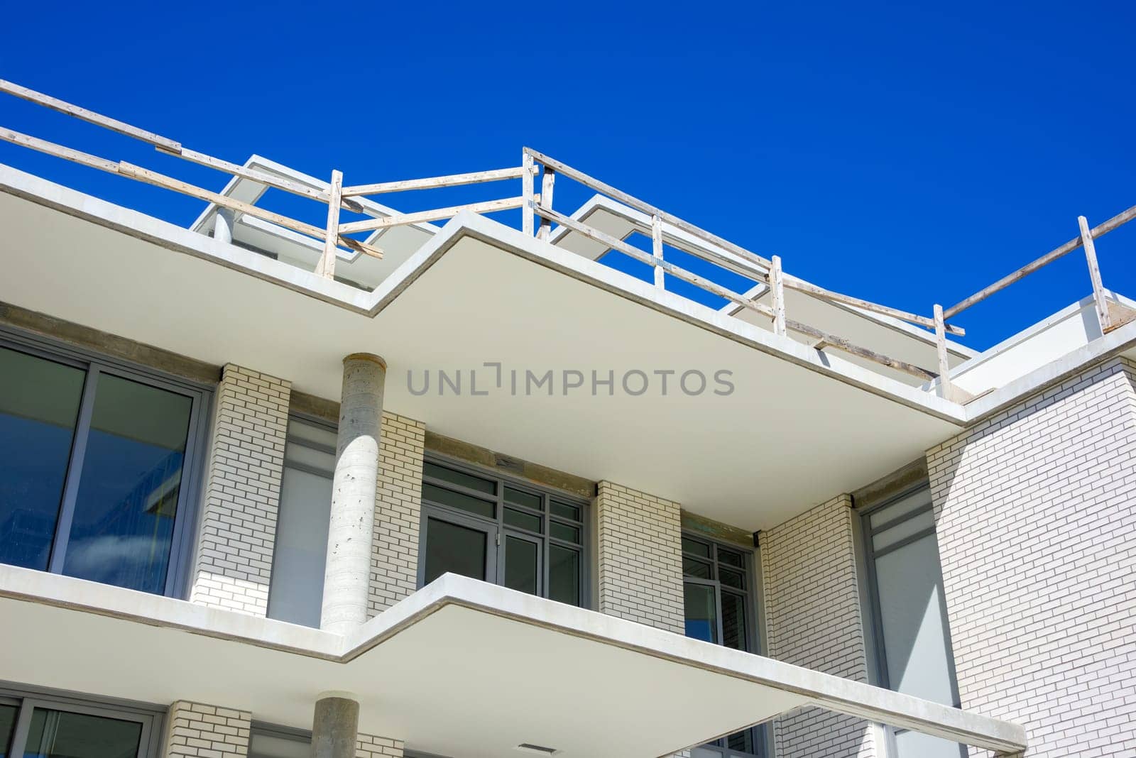 Top of new low-rise residential building under construction on blue sky background.