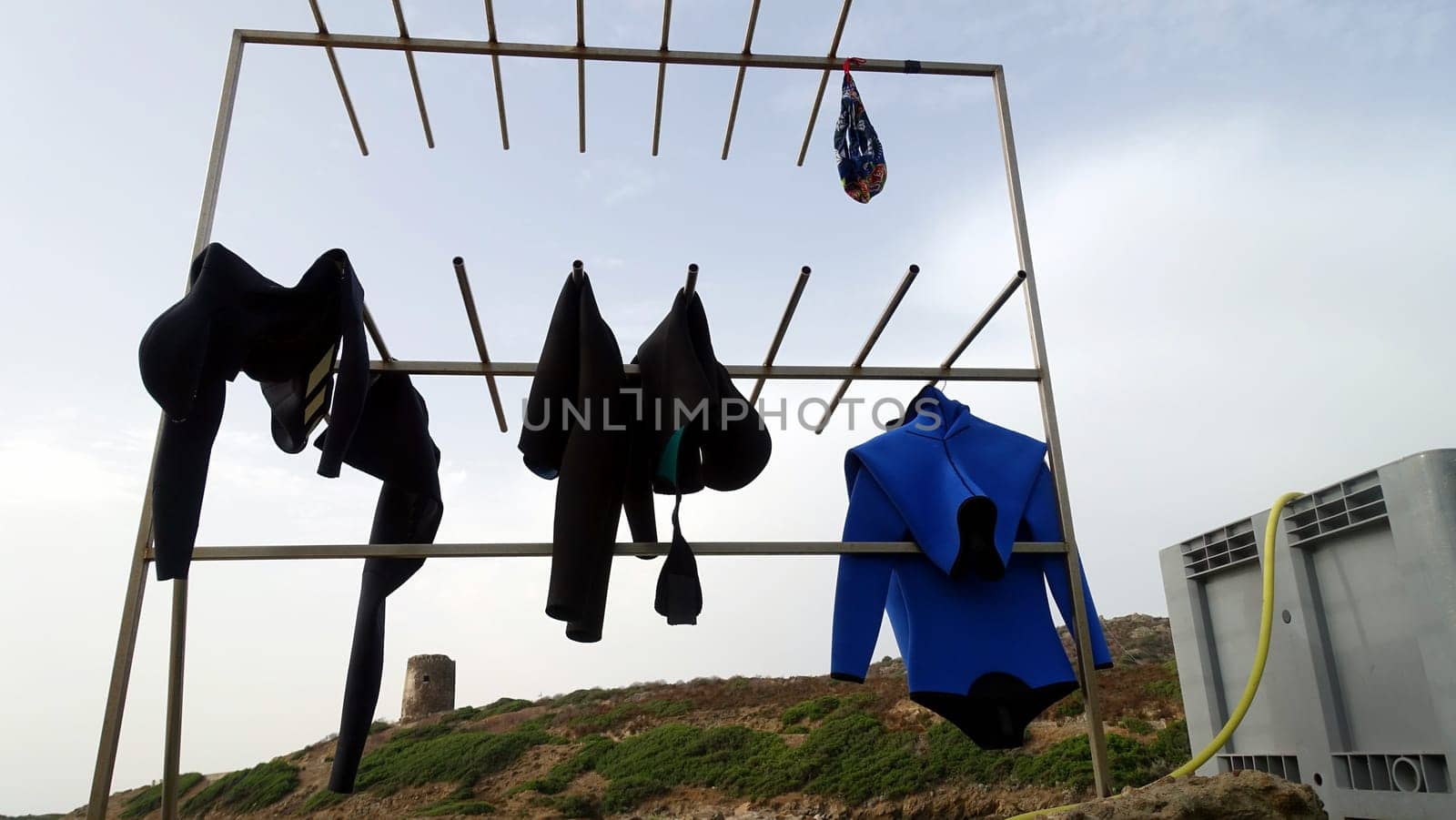 Diving suits and a swimsuit hanging out to dry in the sun after an intense day in the water.