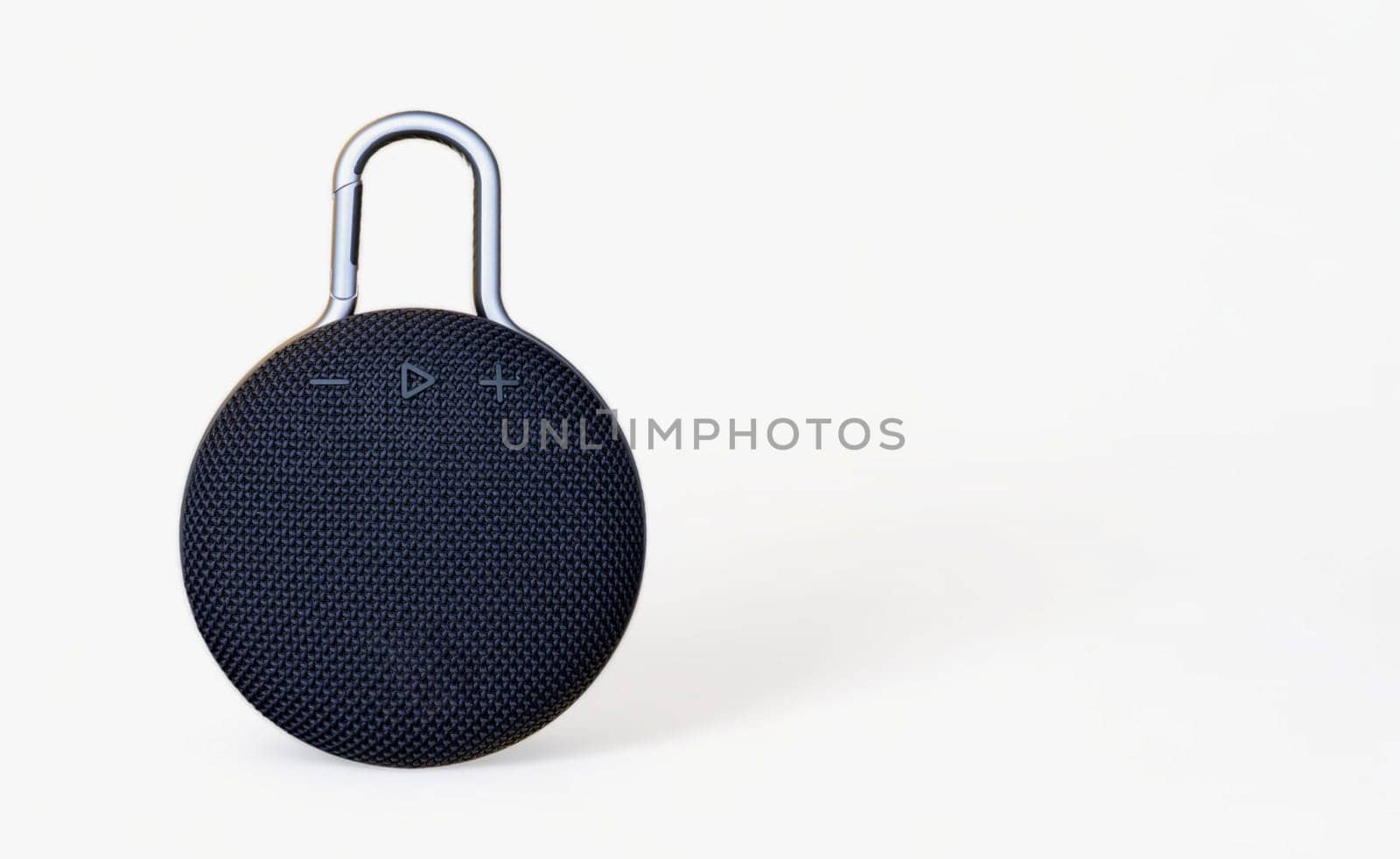 Waterproof round black speaker with carabiner. Digital music and sound concept. Mini, suitable for travel. Modern technology concept. Smart portable wireless speaker on a white background. by Roshchyn