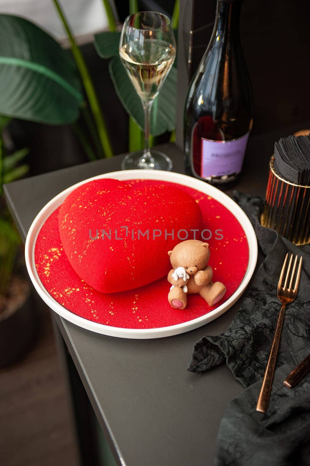 Heart Shaped Red Velvet Valentine's Day Cake with a bottle of sparkling wine and a glass in a restaurant. High quality photo