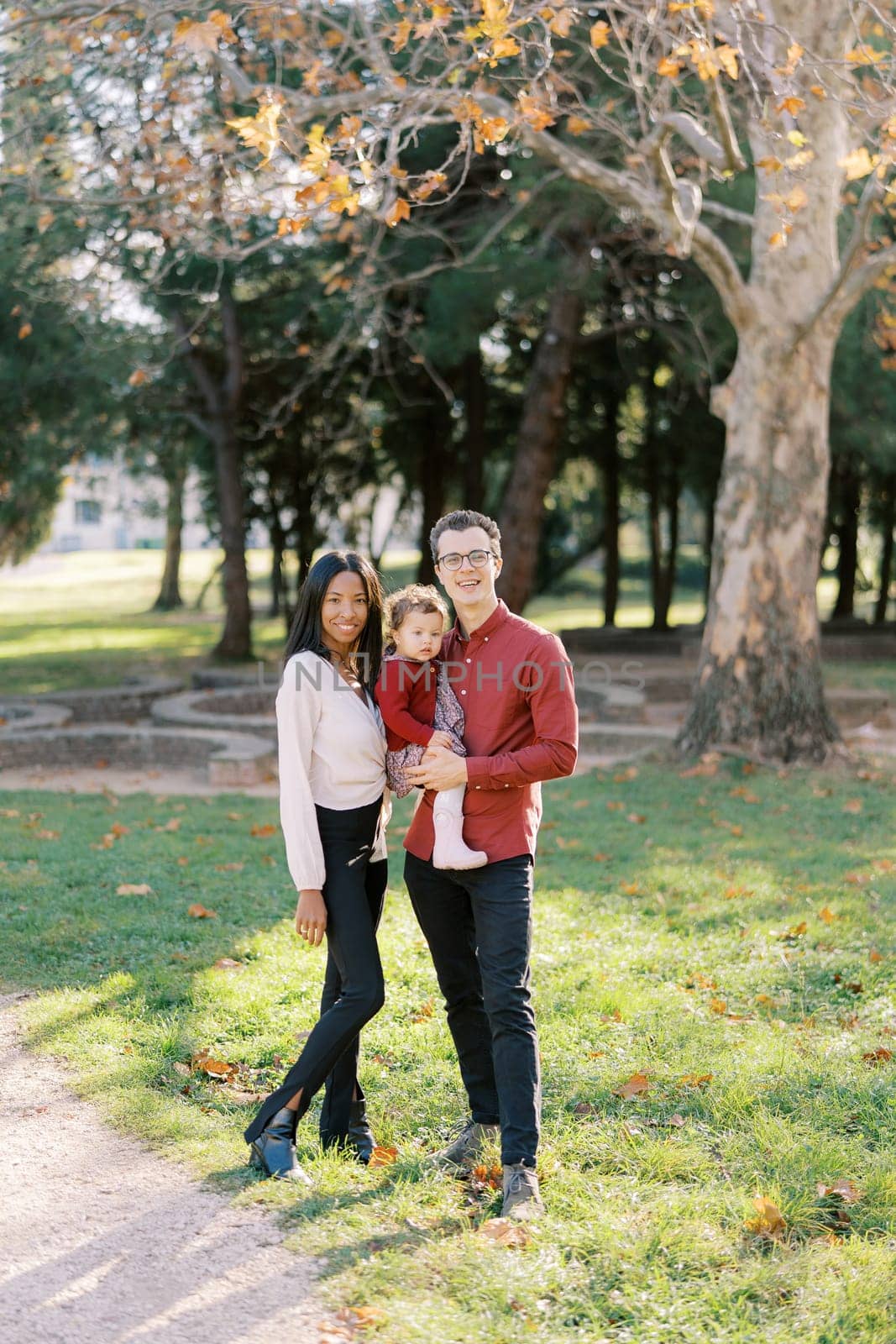 Mom stands next to dad holding a little girl in the park. High quality photo