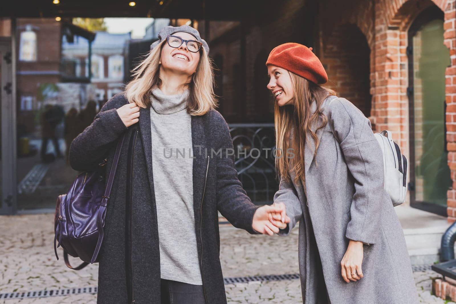 Young pretty girls friends having fun outdoor in autumn evening in city laughing and going crazy fooling on the street - friendship and funny people concept by Satura86