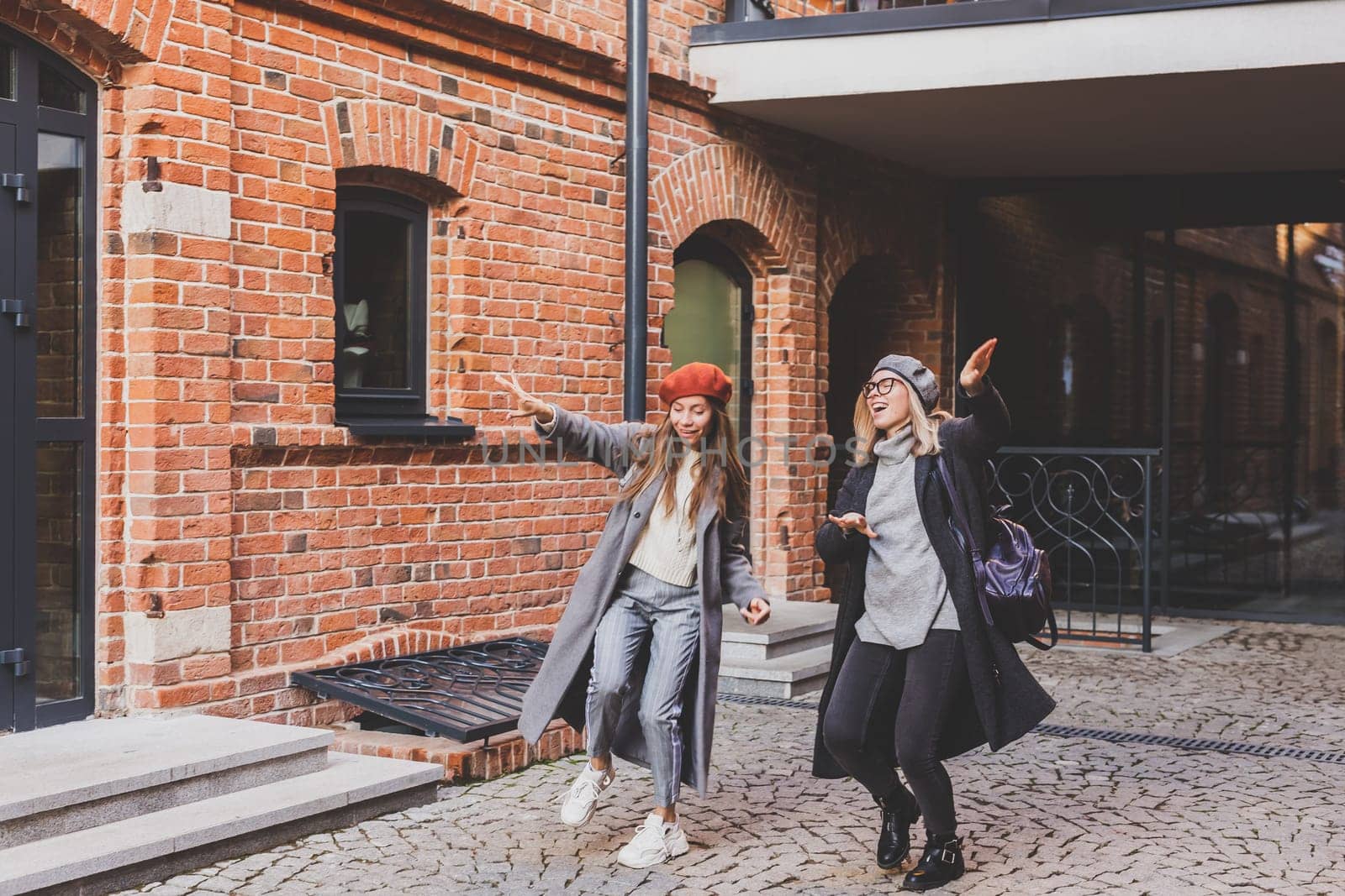 Millennial young women having fun and dance on city street. Female friends enjoying autumn day around the city.