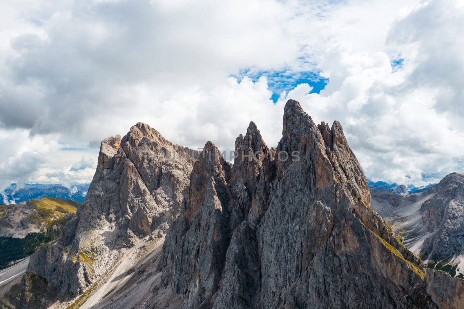 Bare peak and steep slopes of Seceda mountain range against cloudy sky. Observation deck overlooking giant ridgeline in Alps aerial view