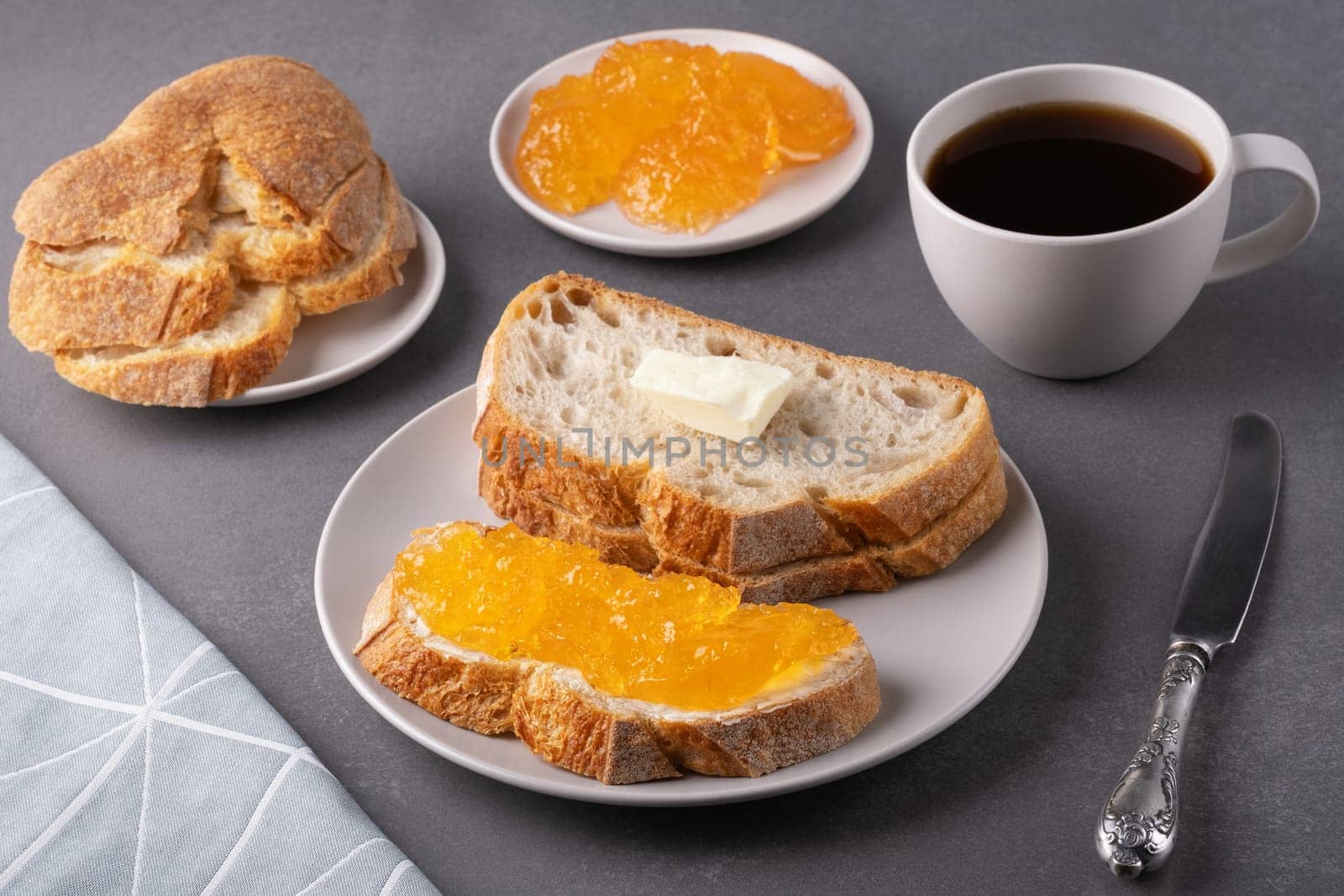 Sandwiches with apricot jam and a cup of coffee on a gray background. Breakfast concept.