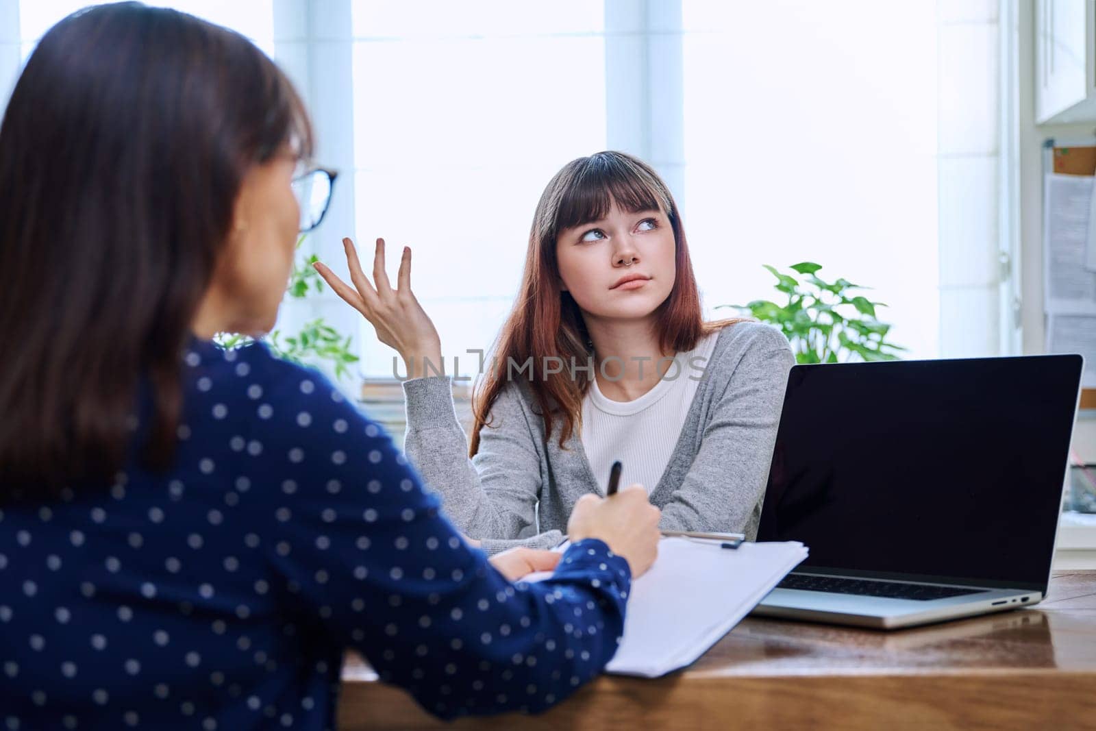 Sad, serious teenage girl at session in office of mental professional by VH-studio