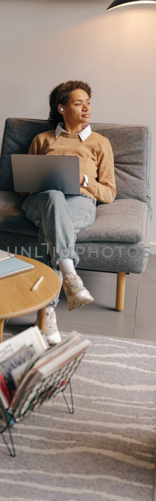 Pretty female sales manager working on laptop while sitting in cozy coworking and looks away