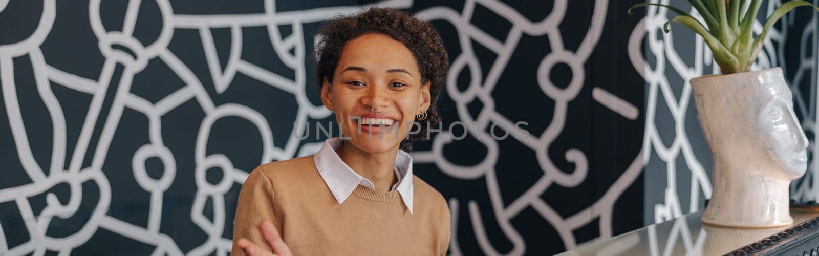 Pretty female office worker standing on reception in office hall and looks camera with smile by Yaroslav_astakhov