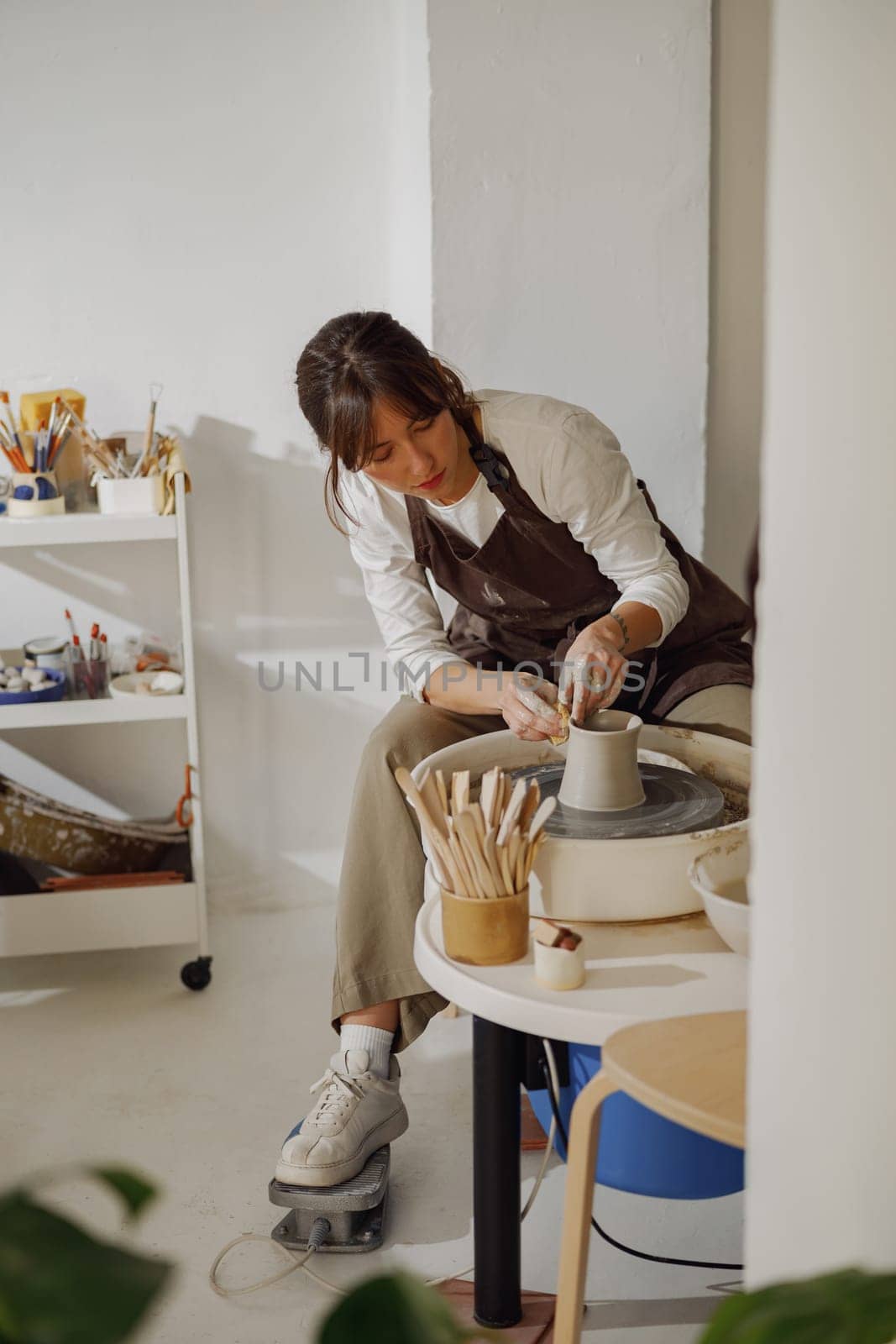 Professional female artisan shaping clay bowl in pottery studio. Ceramics art concept by Yaroslav_astakhov