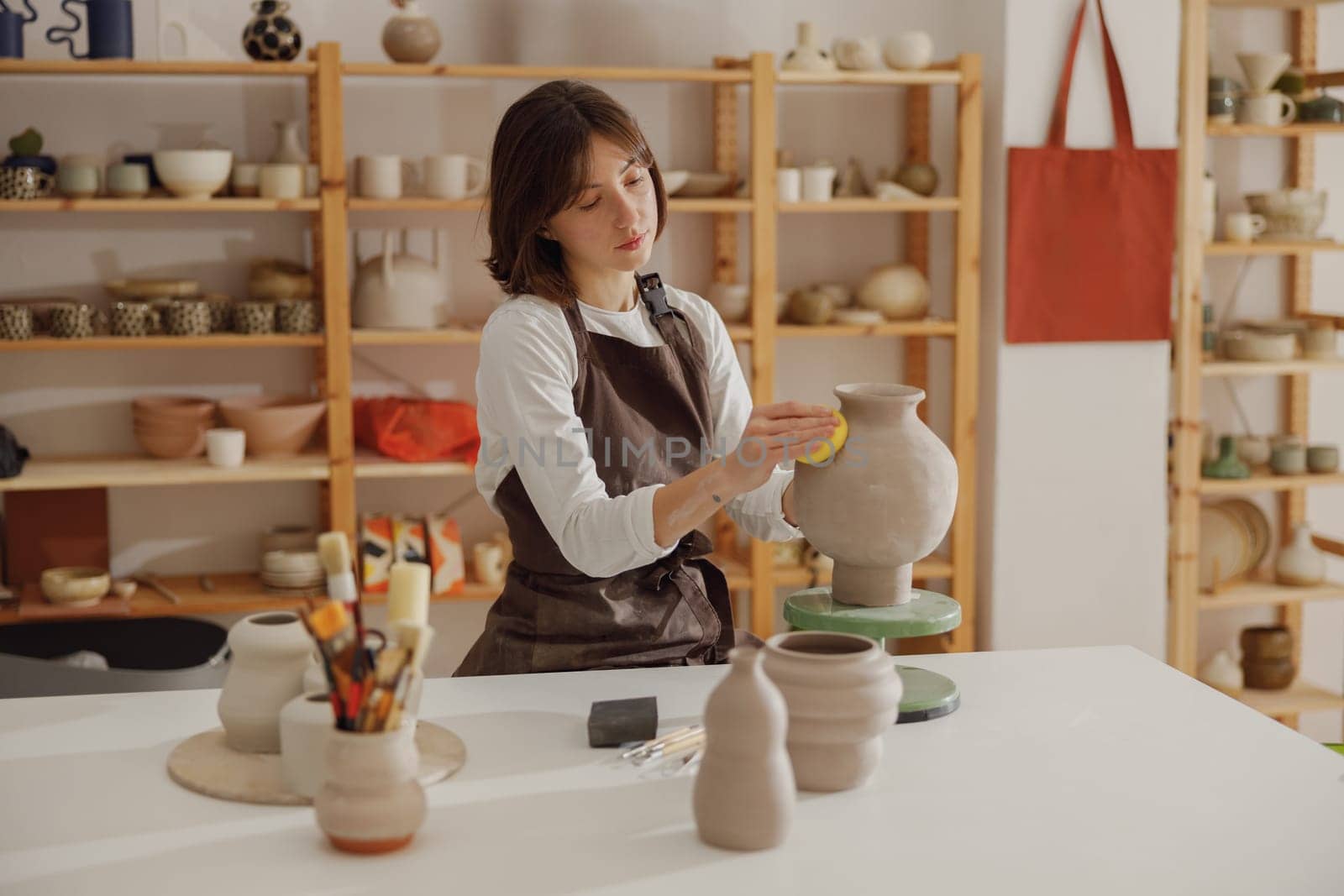 Professional female ceramist work with unfired clay vase in pottery studio. High quality photo by Yaroslav_astakhov