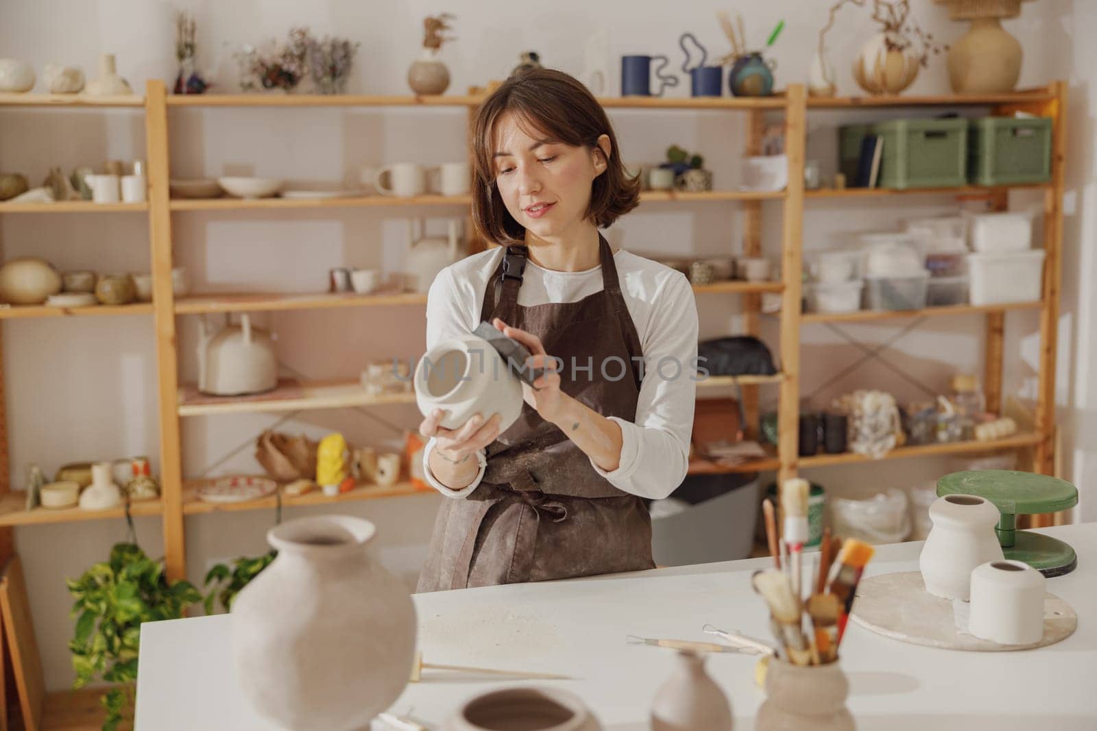 Professional female ceramist work with unfired clay vase in pottery studio. High quality photo