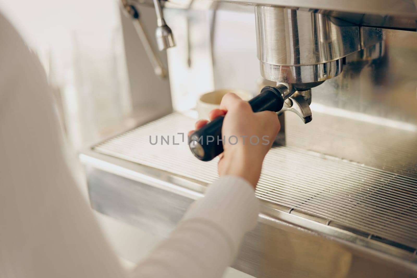 Close up of female barista making coffee in a coffee machine while working in cafe by Yaroslav_astakhov