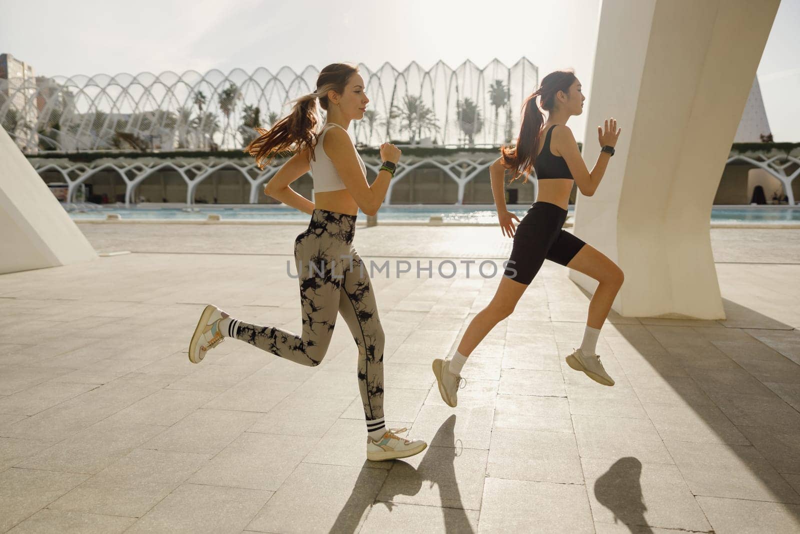 Sporty female friends in sportswear running outdoors on a sunny day . Morning jog