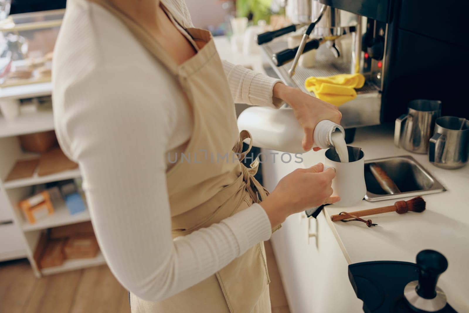 Close up of barista pouring milk into metal pitcher for making cappuccino . High quality photo