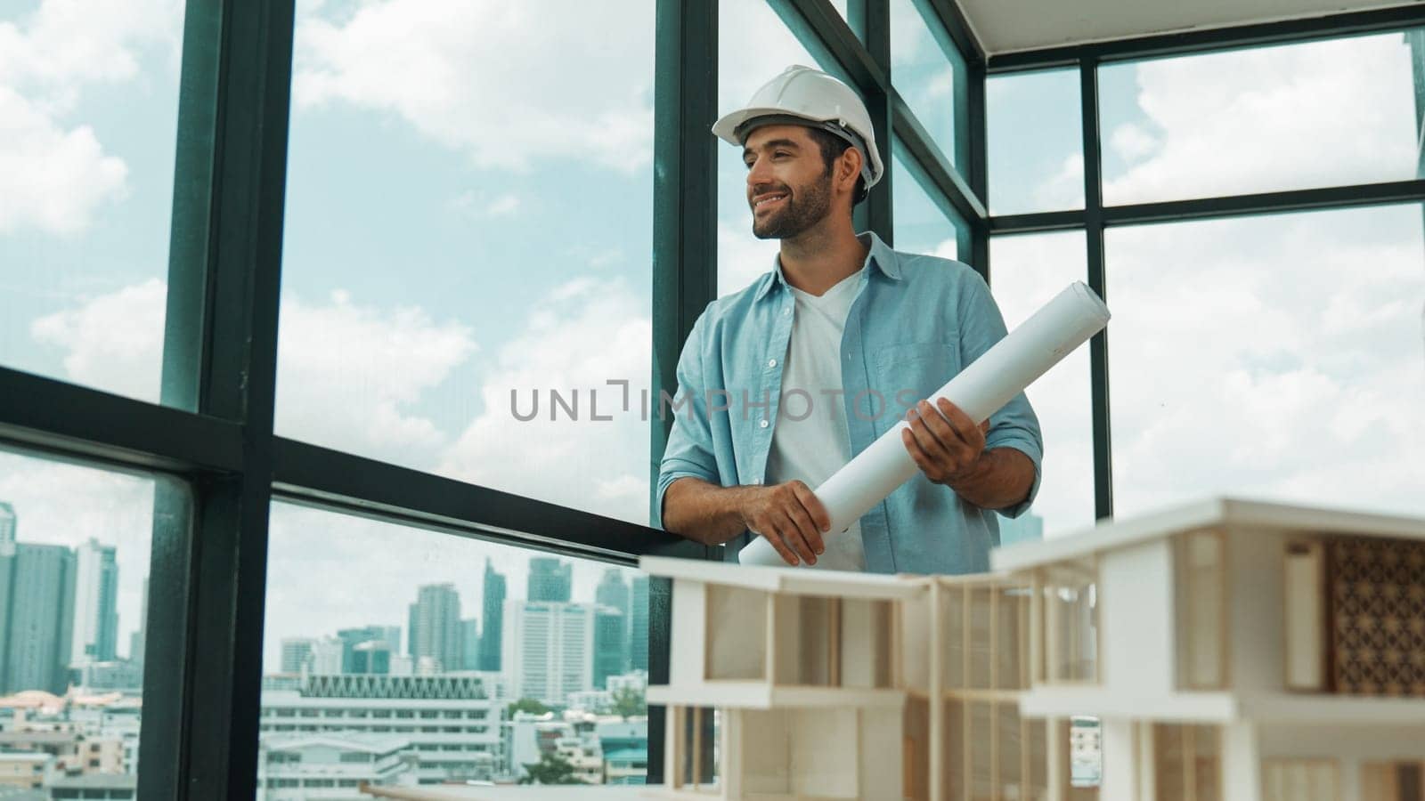 Smart civil engineer standing, walking while looking at house model and architectural equipment. Engineer with safety helmet standing near city view while standing near building model. Tracery