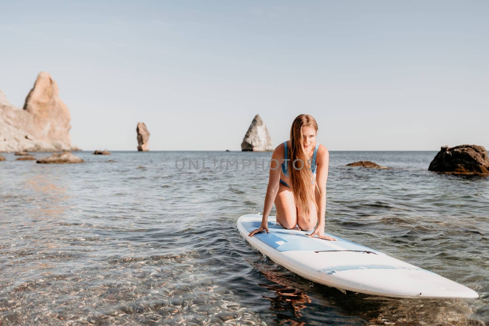 Close up shot of happy young caucasian woman looking at camera and smiling. Cute woman portrait in bikini posing on a volcanic rock high above the sea