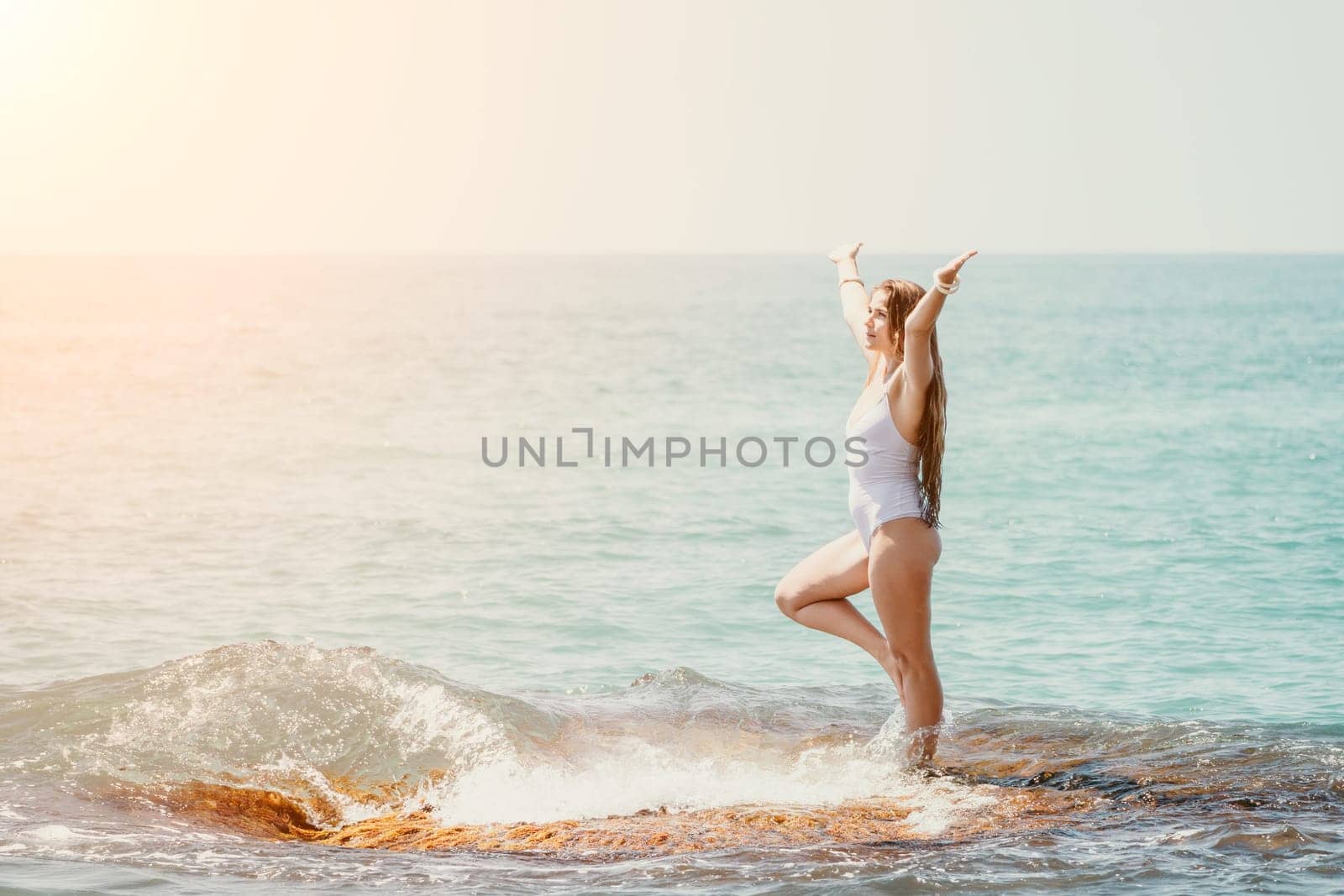 Woman sea yoga. Back view of free calm happy satisfied woman with long hair standing on top rock with yoga position against of sky by the sea. Healthy lifestyle outdoors in nature, fitness concept.