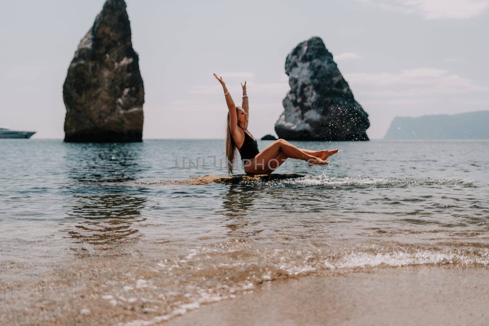 Woman travel sea. Young Happy woman in a long red dress posing on a beach near the sea on background of volcanic rocks, like in Iceland, sharing travel adventure journey