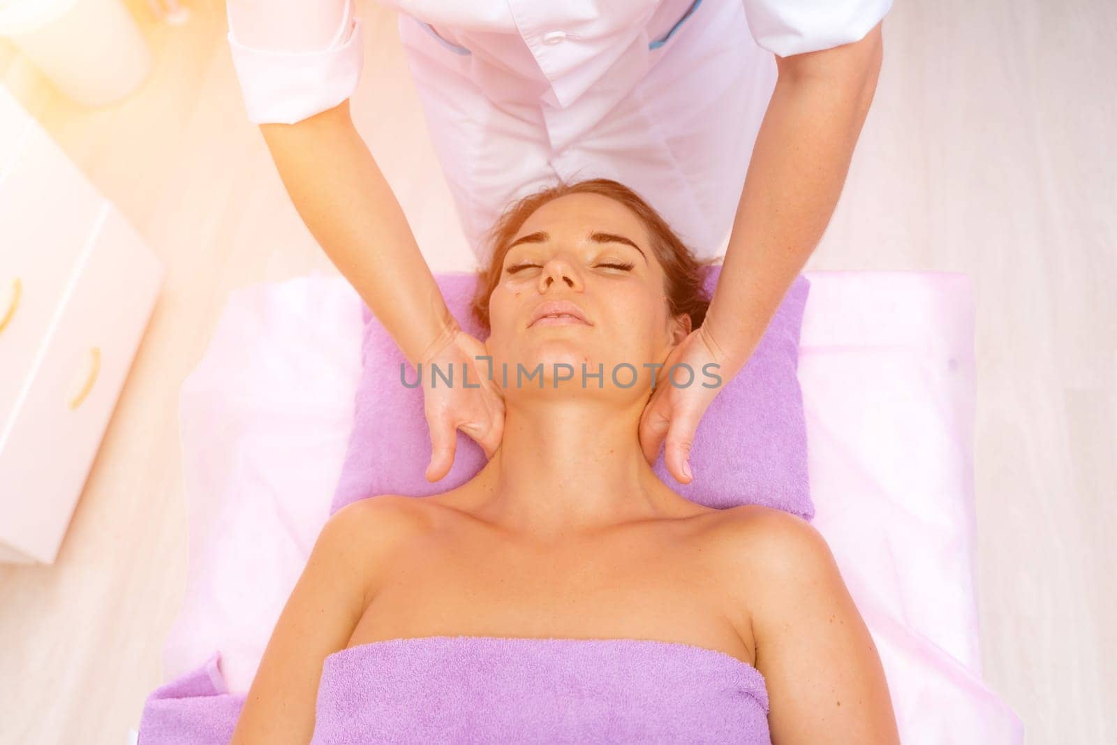 Relaxing massage. European woman getting facial massage in spa salon, side view.