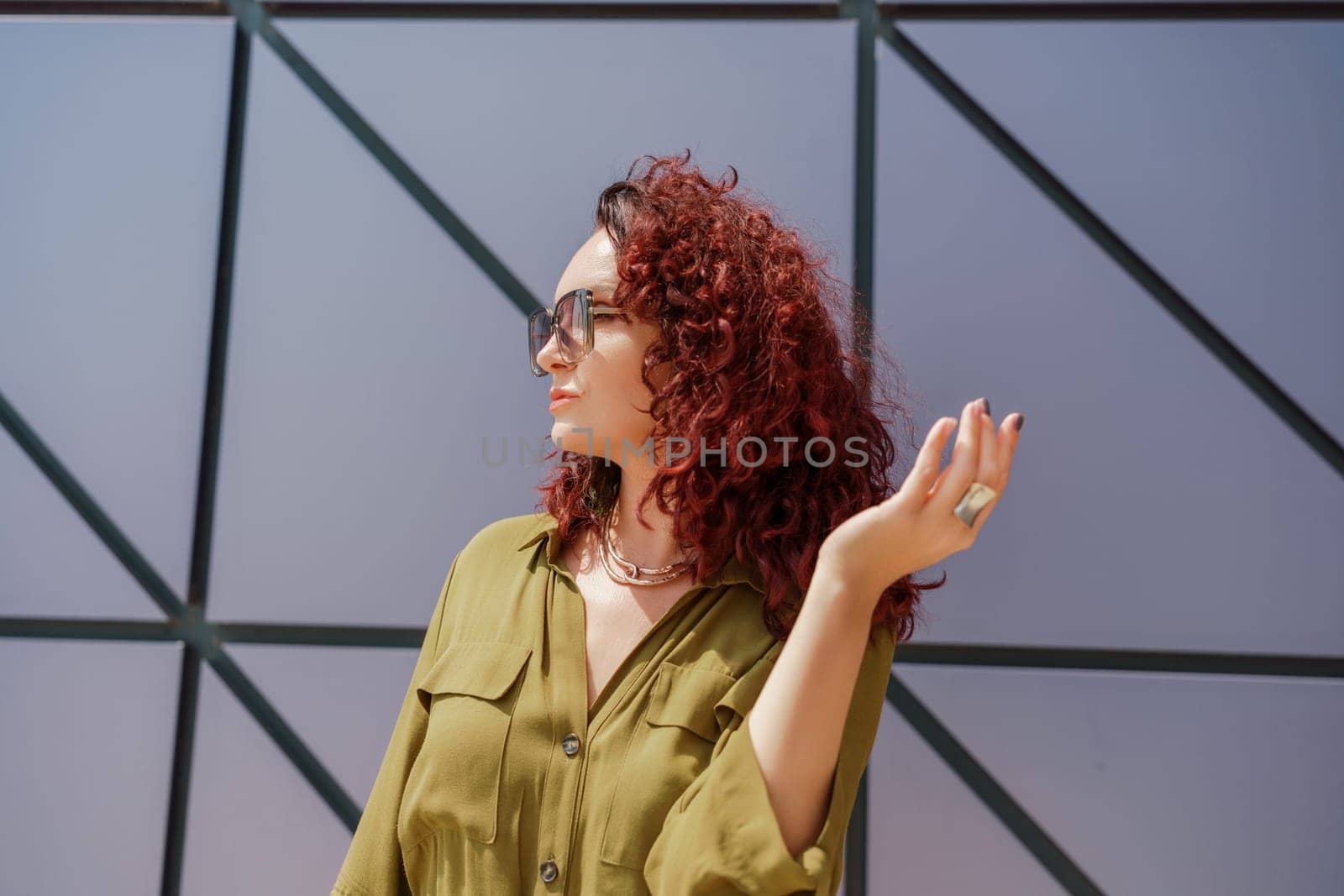 Portrait of a woman standing near a supermarket building. Caucasian model with long brunette hair, wears sunglasses and a khaki dress. by Matiunina