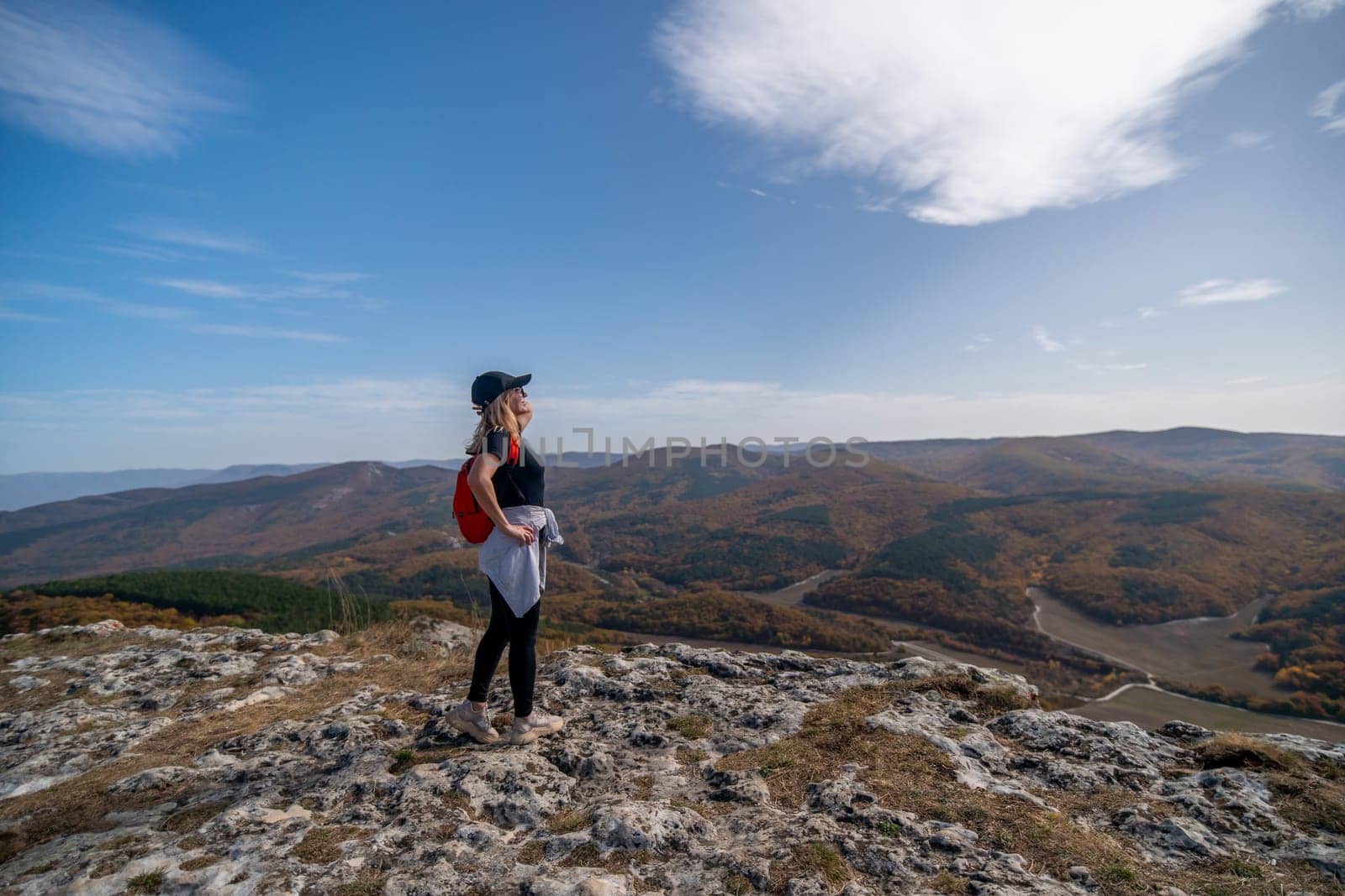 woman backpack on mountain peak looking in beautiful mountain valley in autumn. Landscape with sporty young woman, blu sky in fall. Hiking. Nature by Matiunina
