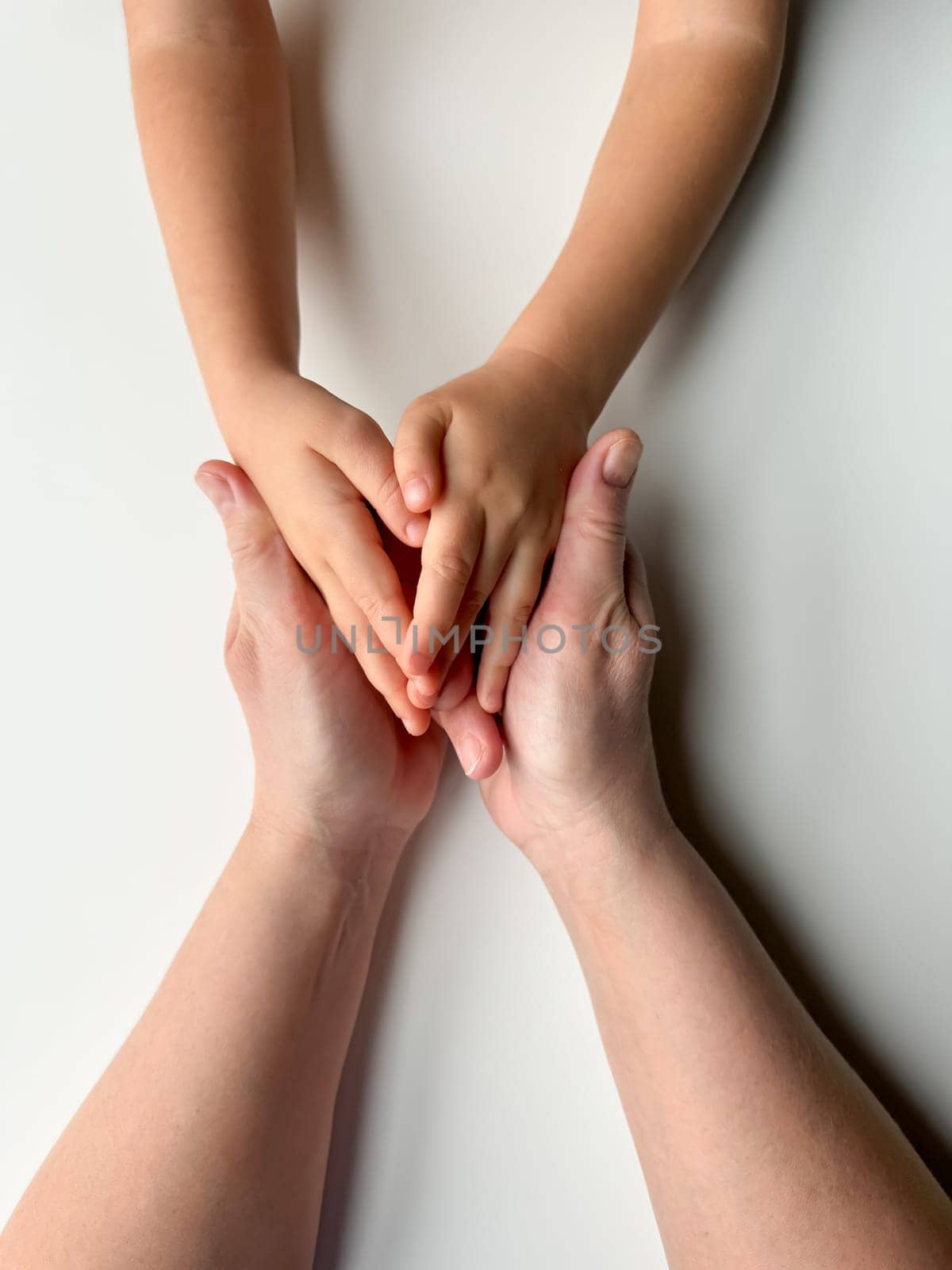 Mothers hands holding childs hands on white background. High quality photo