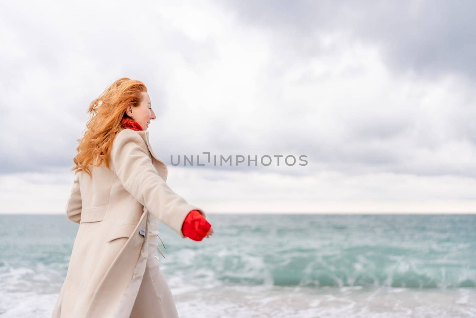 Redhead woman Christmas tree sea. Christmas portrait of a happy redhead woman walking along the beach and holding a Christmas tree in her hands. Dressed in a light coat, white suit and red mittens. by Matiunina