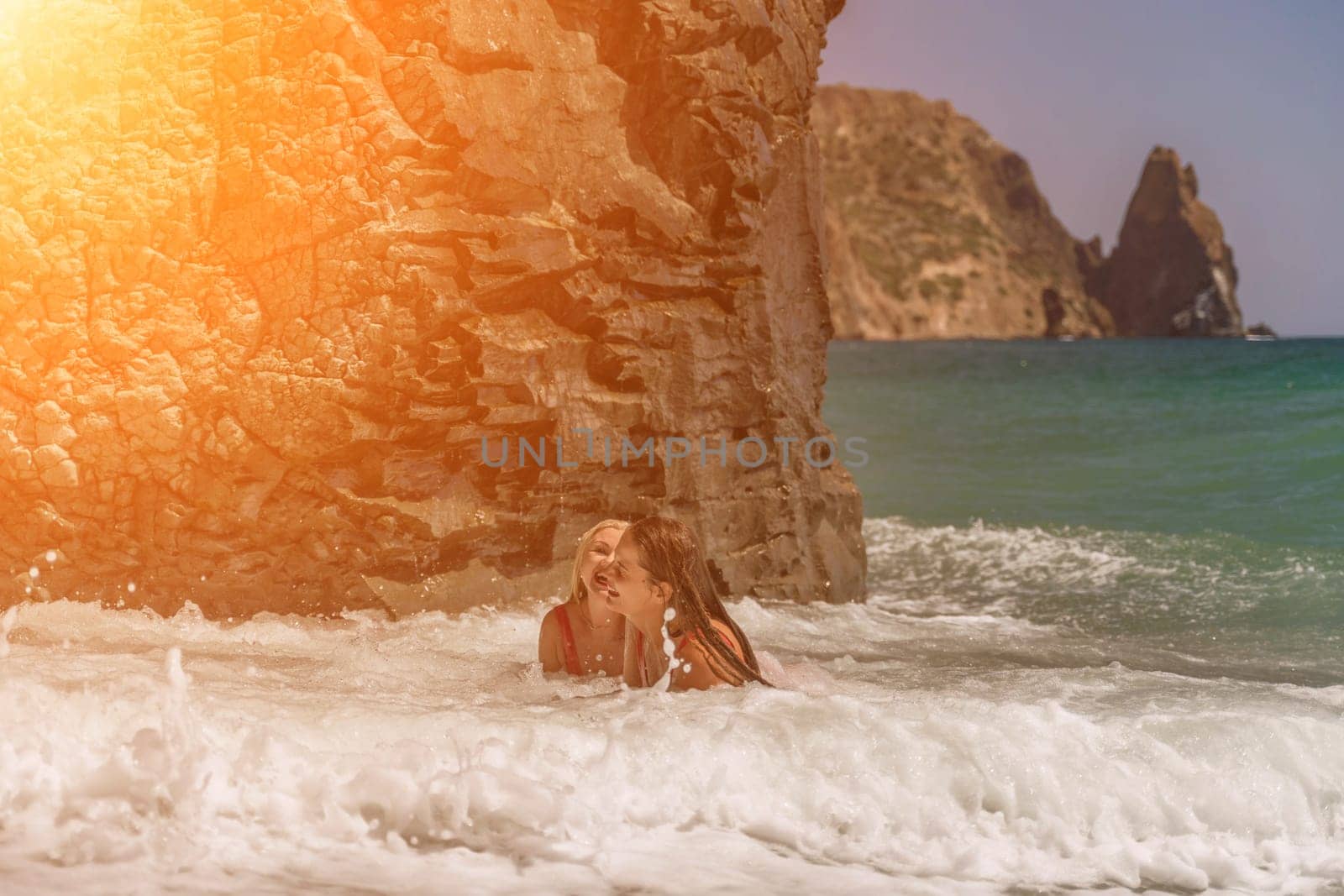 Women ocean play. Seaside, beach daytime, enjoying beach fun. Two women in red swimsuits enjoying themselves in the ocean waves. by Matiunina