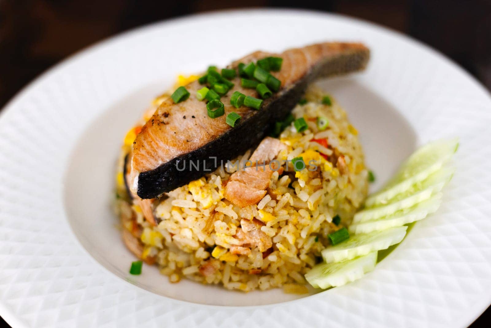 Fried rice with grilled salmon fillet steak on white plate.