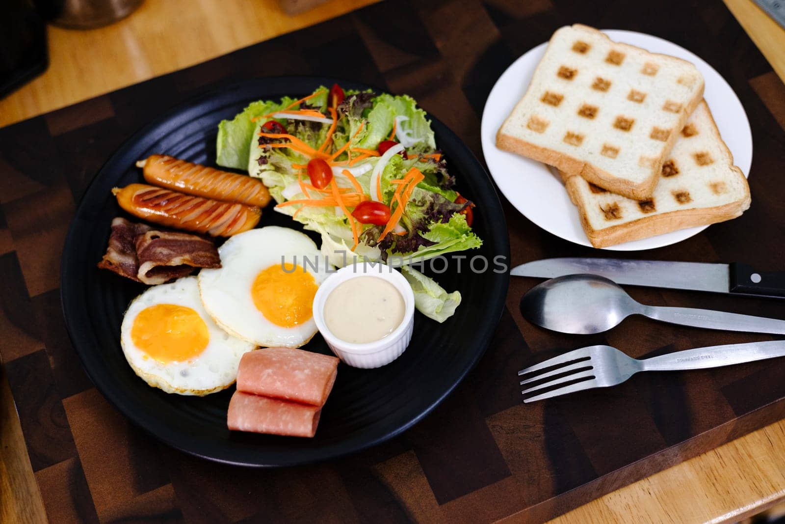 Full breakfast with fried egg, sausage, bacon, ham, toast and salad. Top view