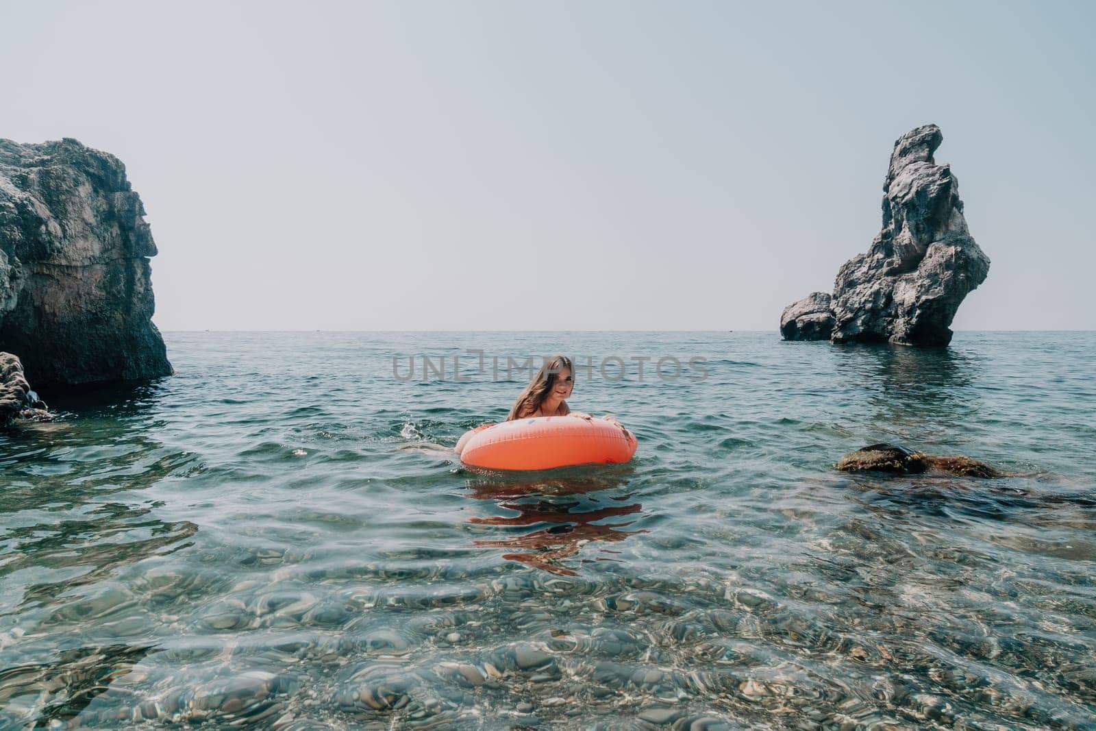 Woman summer sea. Happy woman swimming with inflatable donut on the beach in summer sunny day, surrounded by volcanic mountains. Summer vacation concept. by panophotograph