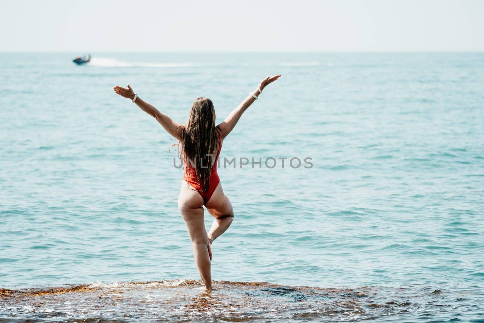 Woman sea yoga. Back view of free calm happy satisfied woman with long hair standing on top rock with yoga position against of sky by the sea. Healthy lifestyle outdoors in nature, fitness concept.