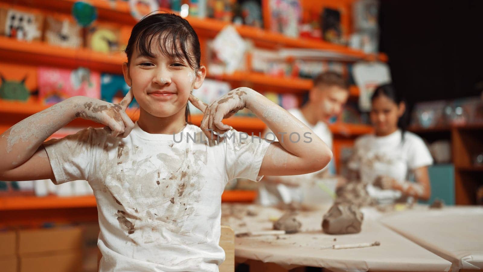 Asian girl pose at camera while diverse children modeling clay. Edification. by biancoblue
