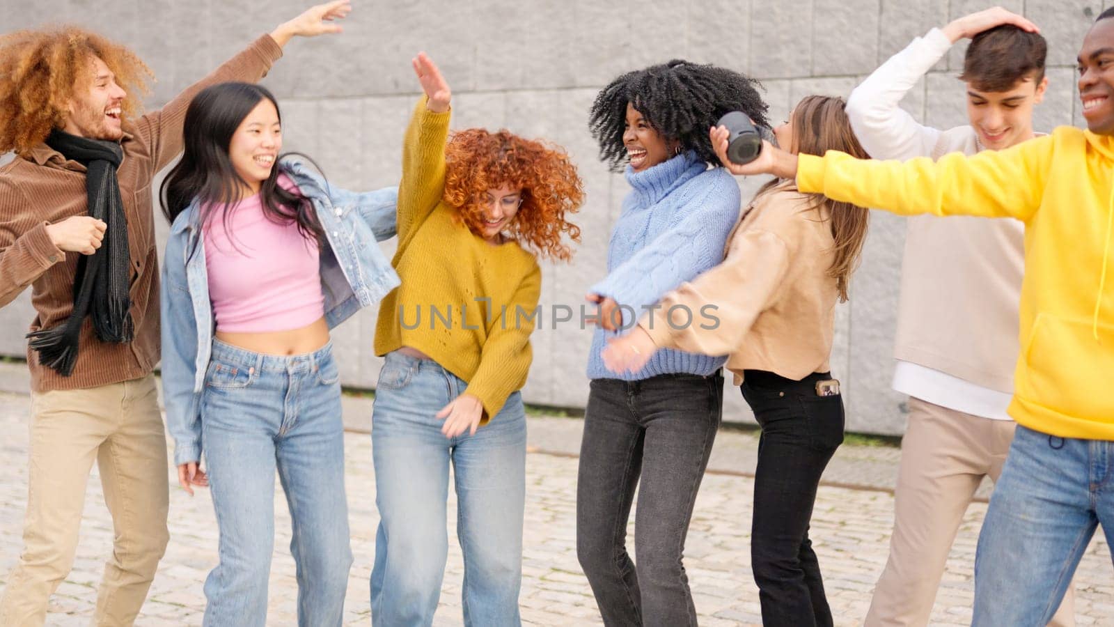 Group of multi-ethnic friends enjoying dancing and celebrating together in the city