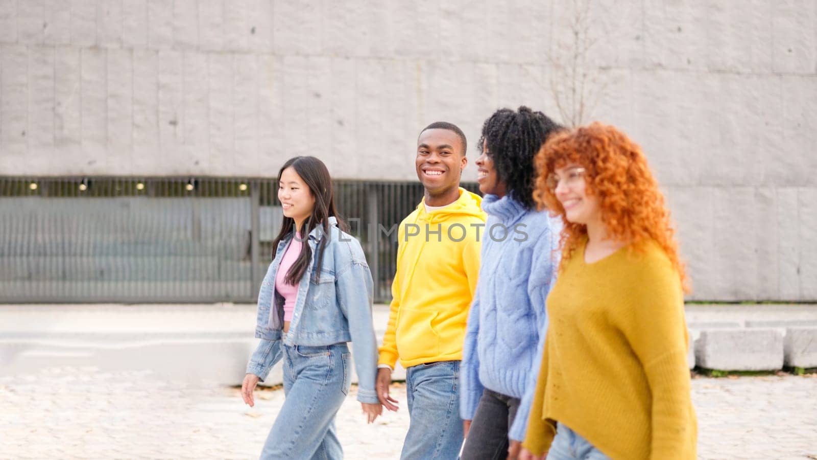 Multiracial friends smiling while strolling along the street