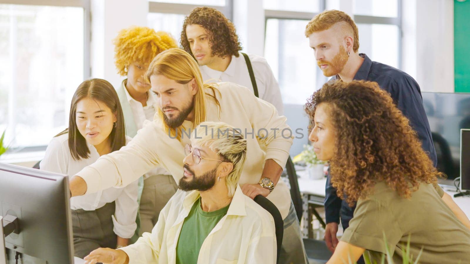 Coworkers talking while looking at a one computer screen by ivanmoreno